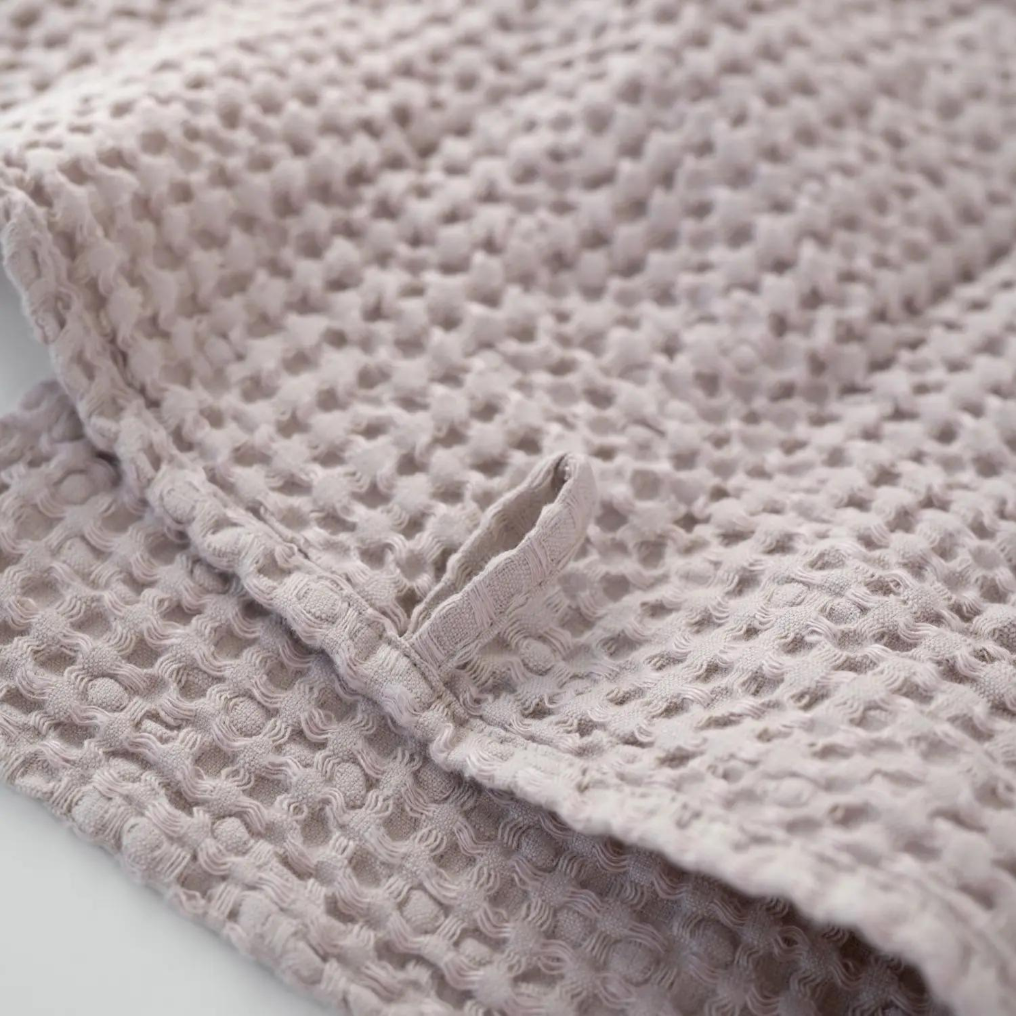 Set of three waffle-textured linen and cotton towels in powder color, showcasing different sizes and a hanging loop.