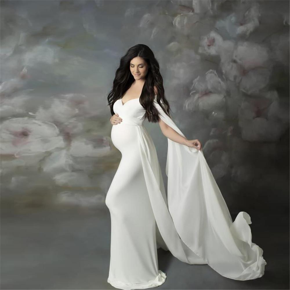 A beautiful pregnant woman wearing a sexy shoulderless maternity dress in chiffon, perfect for photo shoots, showcasing elegance and style.