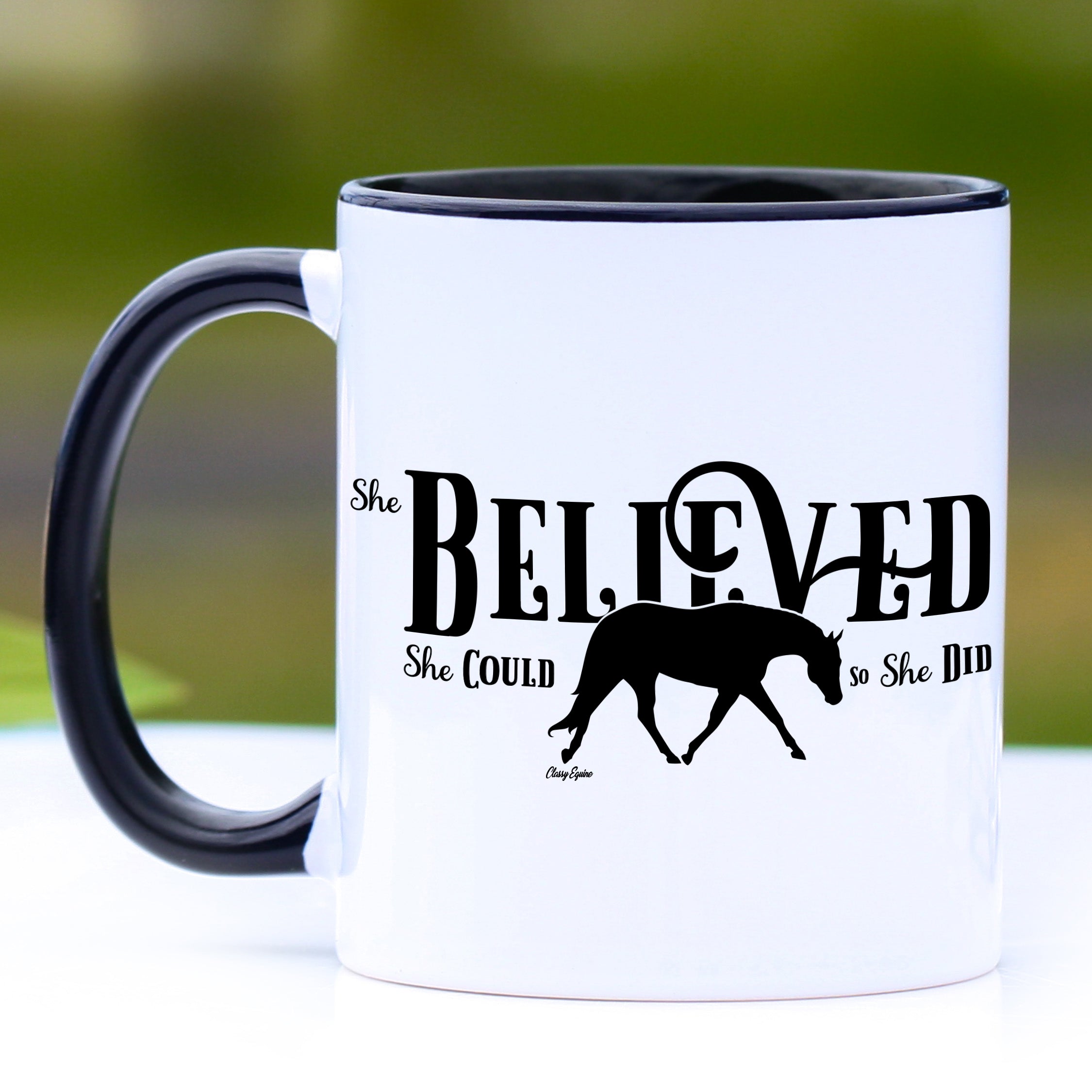 A stylish 11 oz motivational horse mug with a black handle and interior, featuring the quote 'She Believed She Could So She Did'.