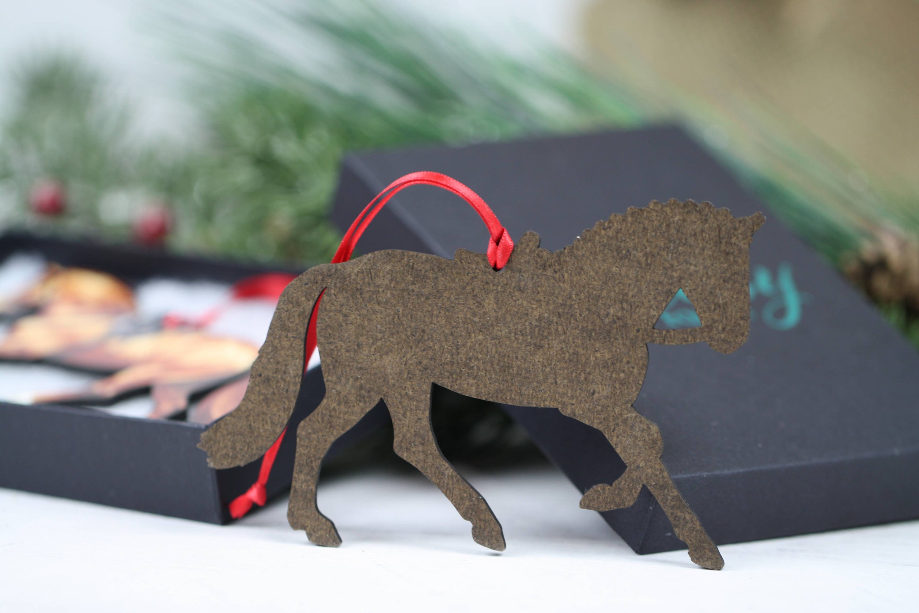 A beautifully crafted Side Saddle Horse Ornament in chestnut color, made from composite wood with a glossy finish, perfect for Christmas decoration.