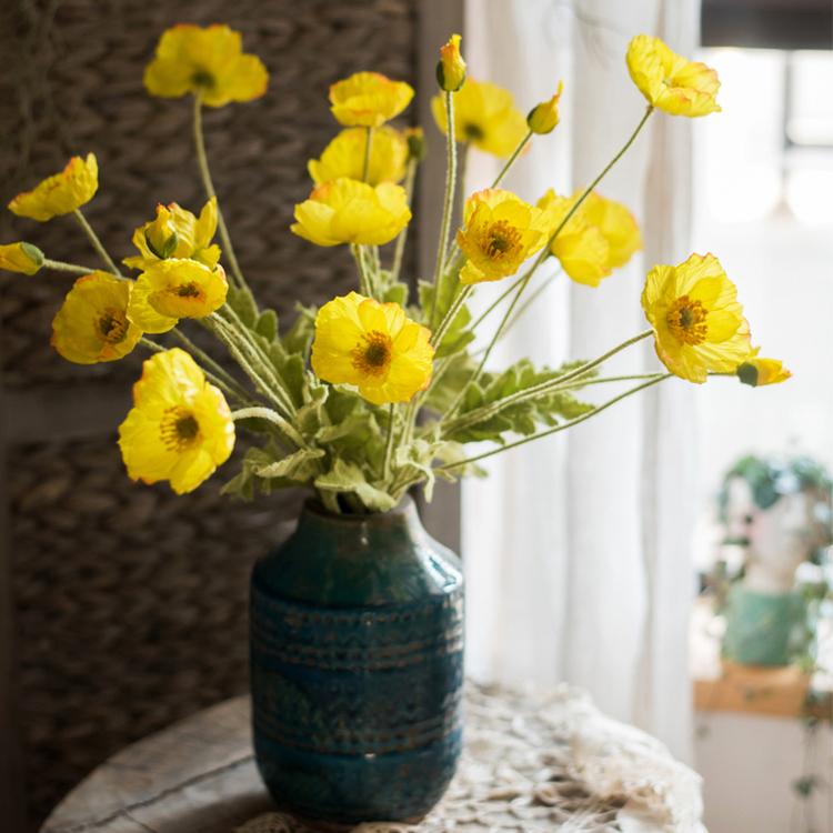 A 22-inch tall Silk Common Poppy Flower Stem featuring vibrant orange, red, and yellow blooms with green leaves, perfect for home decor.