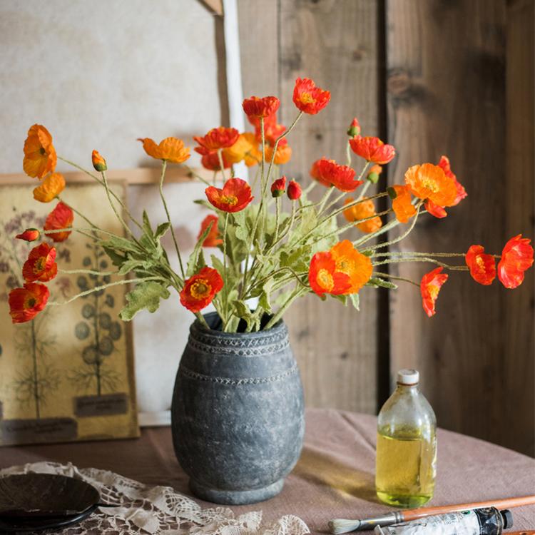 A 22-inch tall Silk Common Poppy Flower Stem featuring vibrant orange, red, and yellow blooms with green leaves, perfect for home decor.