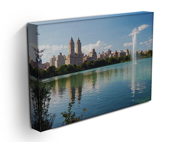 A beautiful canvas print depicting a skyline with skyscrapers and trees, reflecting on a tranquil lake, perfect for modern decor.
