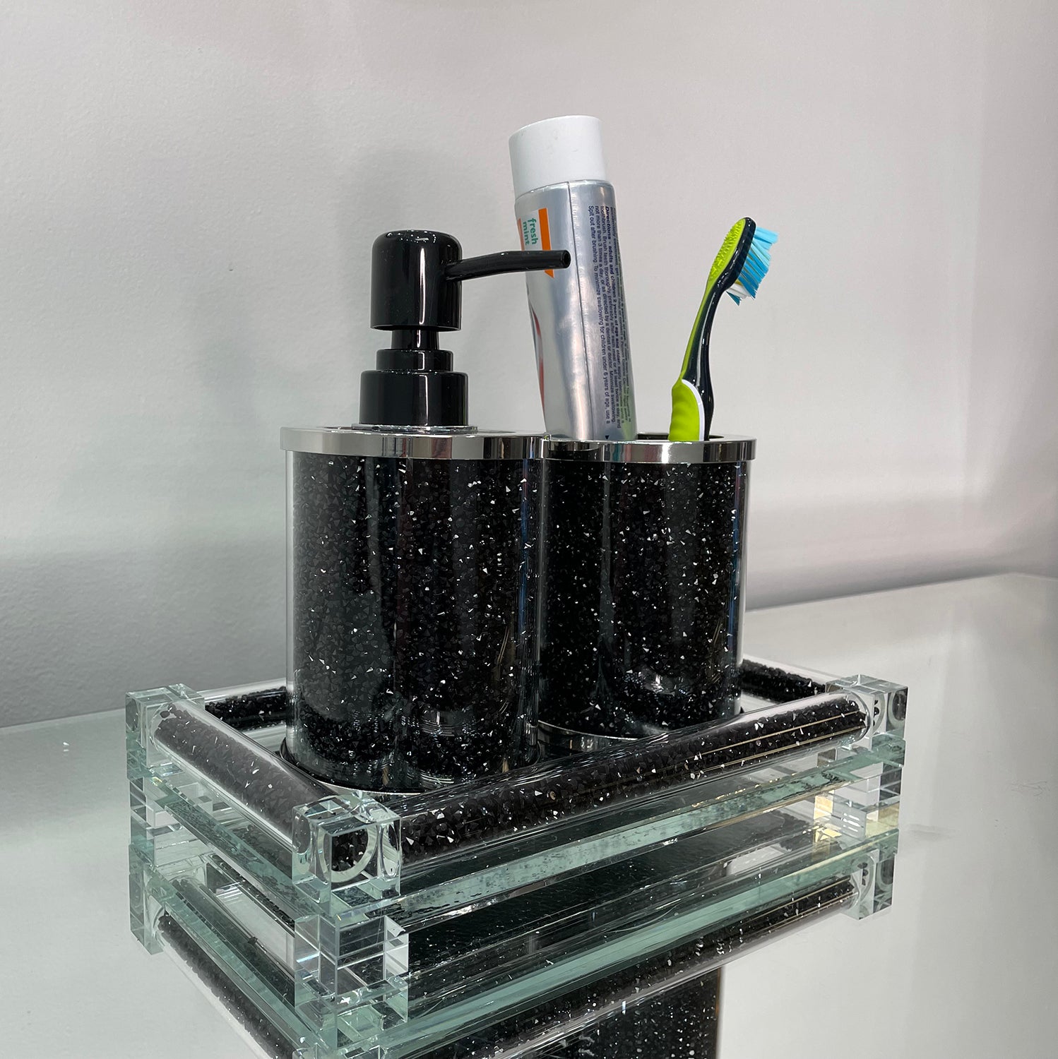 Elegant black crushed diamond soap dispenser and toothbrush holder set with chrome accents, displayed on a tray.
