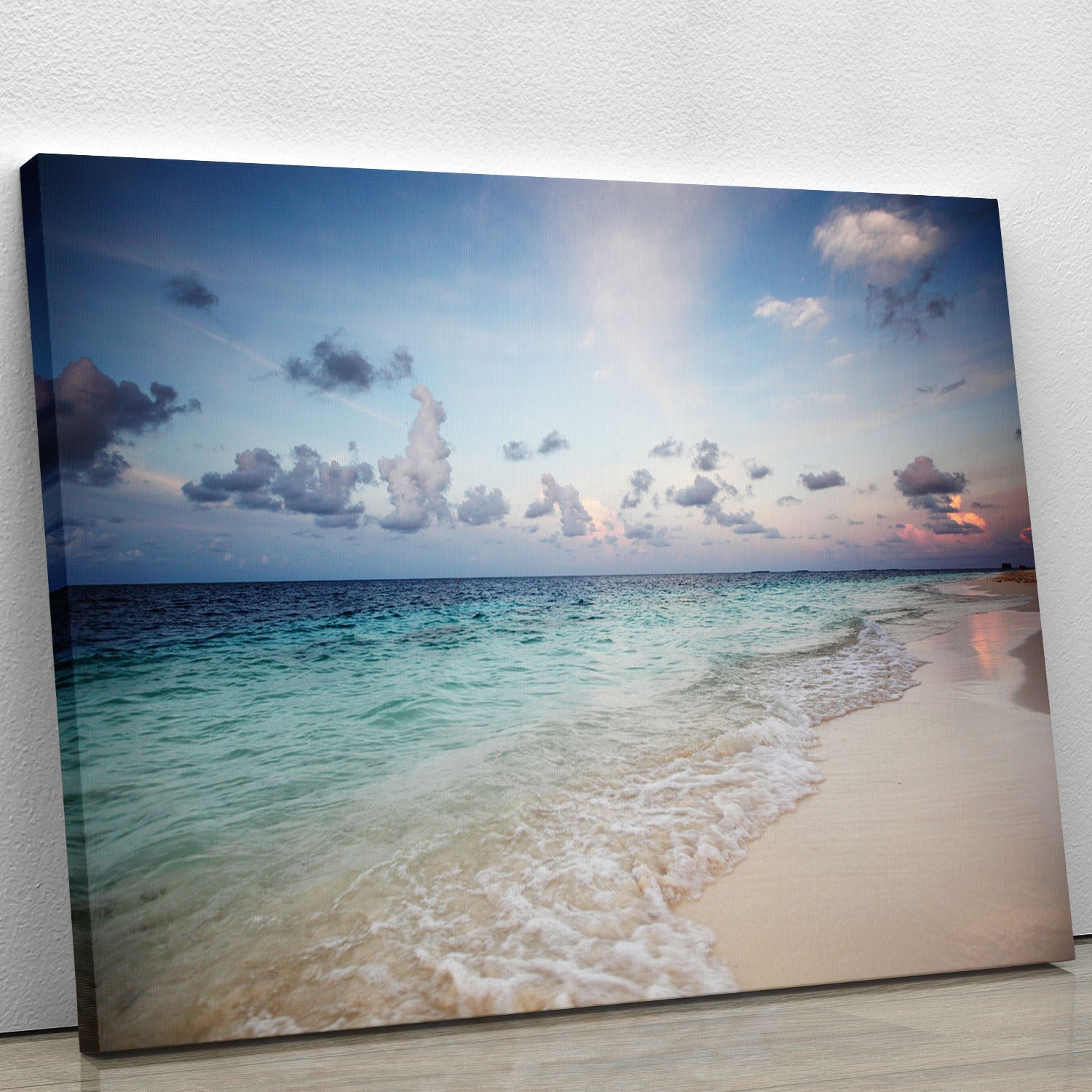 A beautiful canvas print of a sunset over a serene beach, showcasing vibrant colors of orange, pink, and blue reflecting on the water.