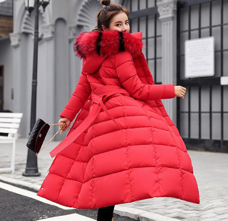 A stylish super long puffy jacket for women featuring a fur hood and multiple pockets, perfect for winter wear.