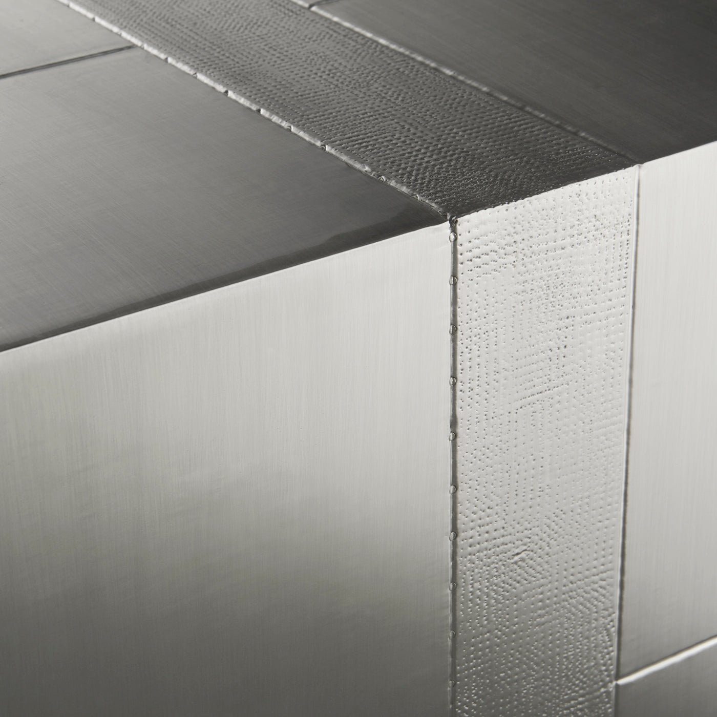 Talitha Six-Drawer Dresser featuring hand-hammered nickel-plated metal with a scratched texture, showcasing a geometric stud pattern and glossy blue interiors.