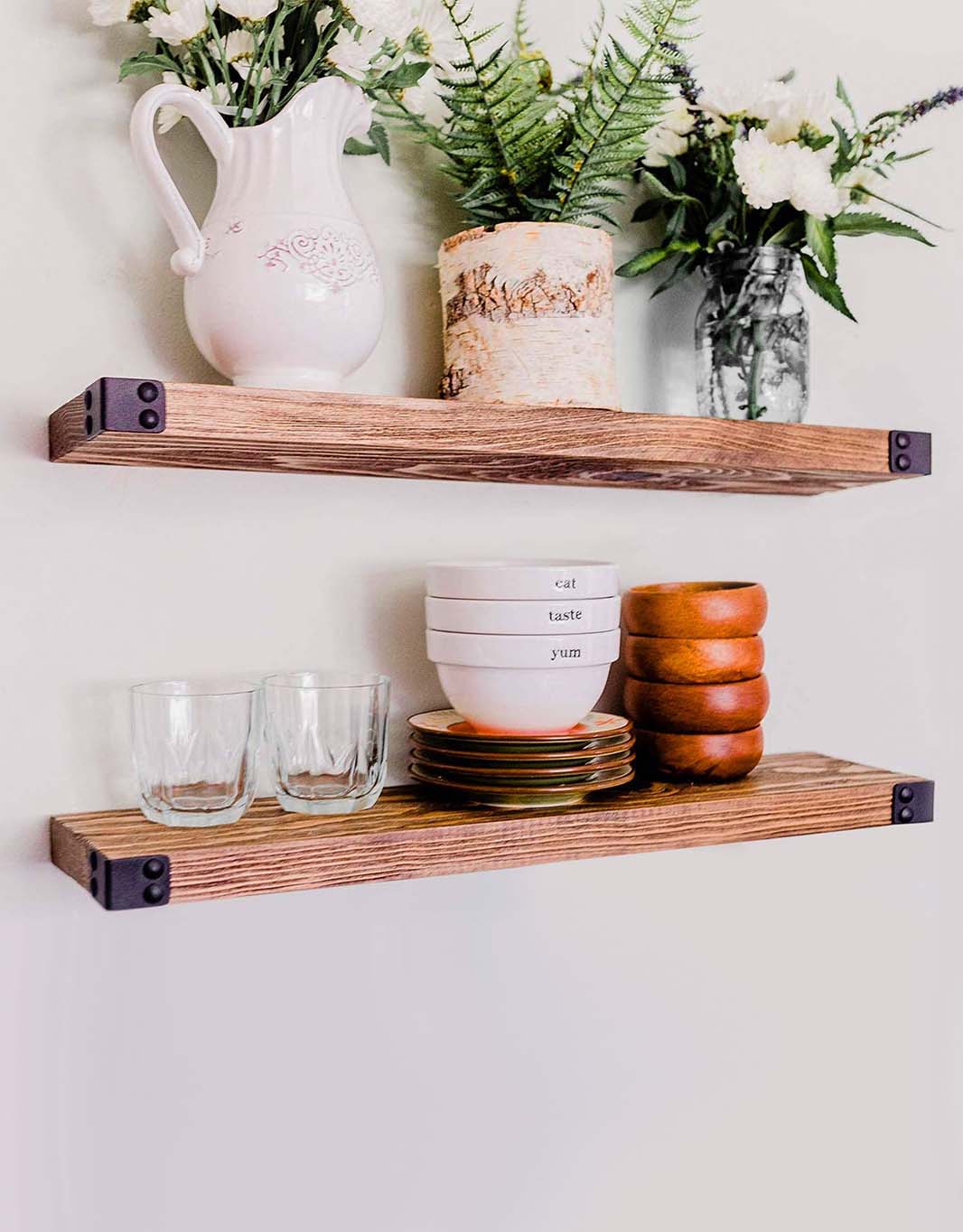 The Dennis floating shelves featuring a light walnut stain and industrial iron corners, showcasing a modern rustic design.