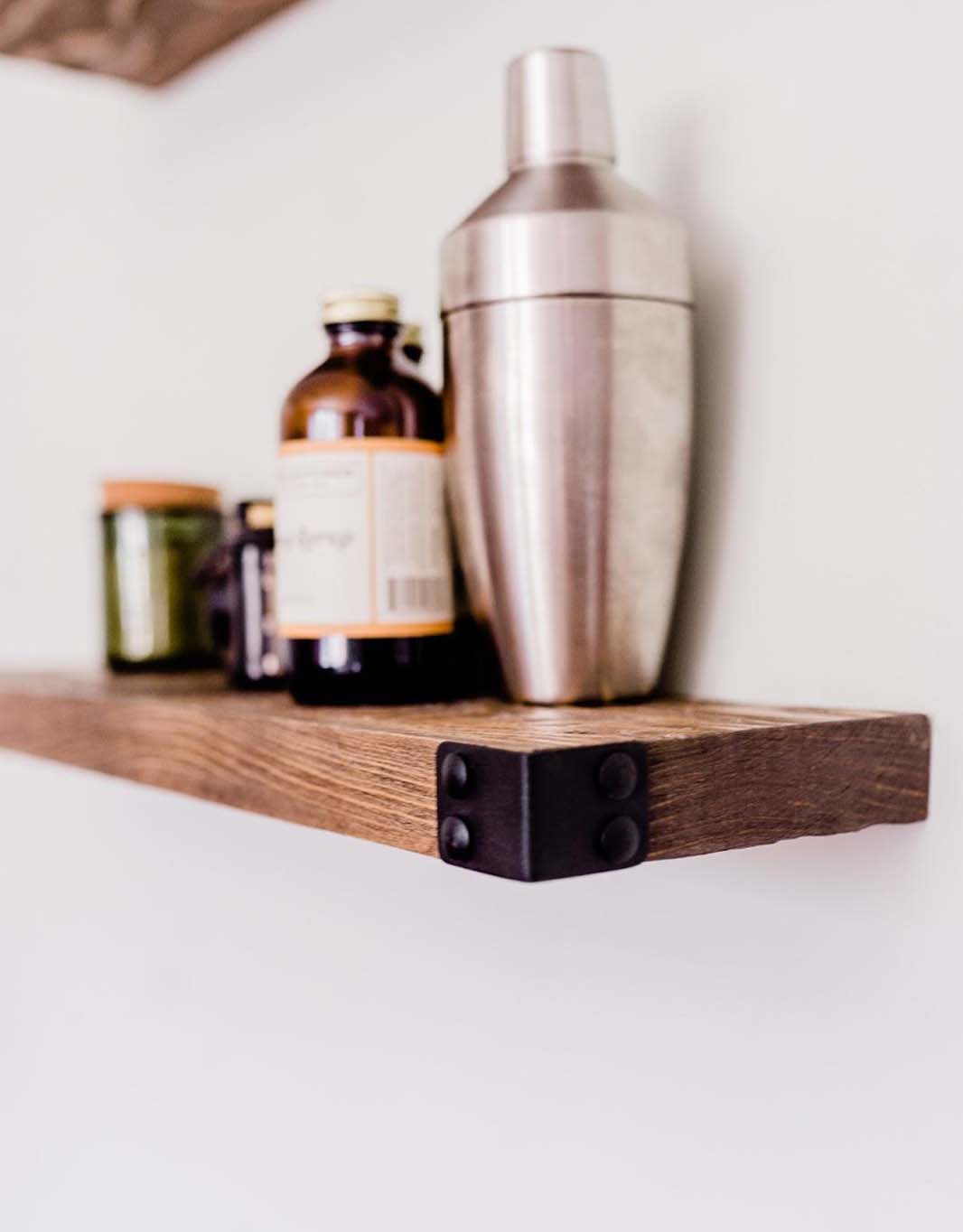 The Dennis floating shelves featuring a light walnut stain and industrial iron corners, showcasing a modern rustic design.