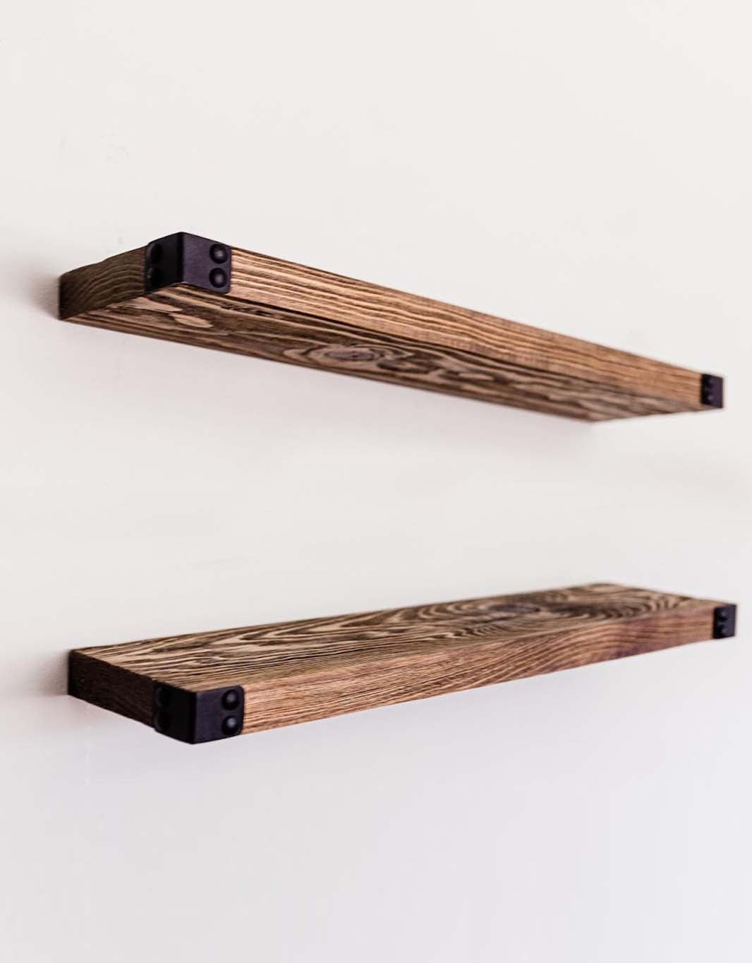 The Dennis floating shelves featuring a light walnut stain and industrial iron corners, showcasing a modern rustic design.