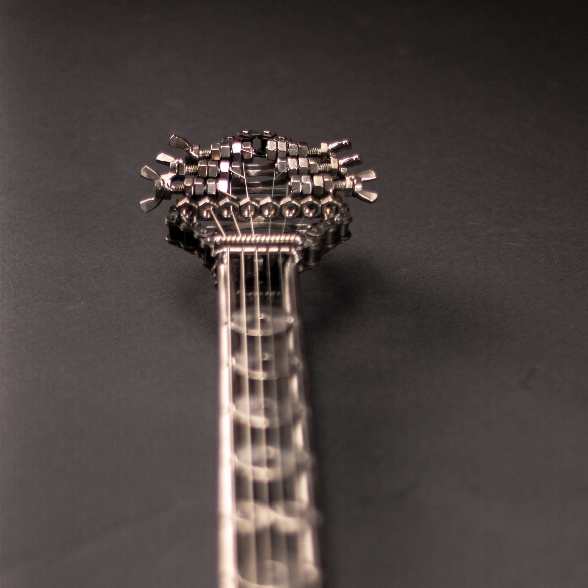 Handmade metal electric guitar sculpture, life-size, crafted from scrap metal with a clear finish.