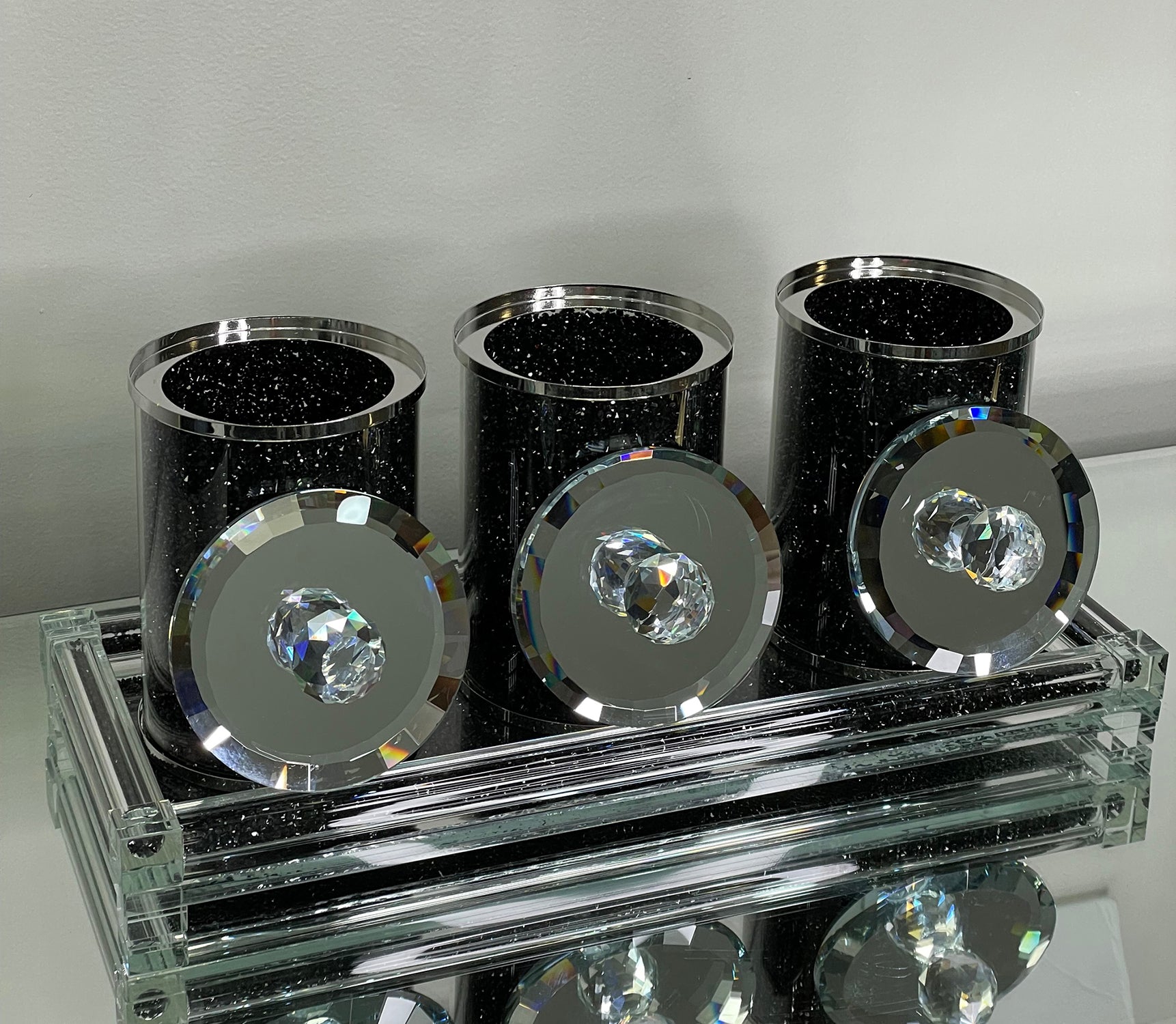 Three glass canisters on a tray, featuring black crushed diamond glass design with elegant glass lids.