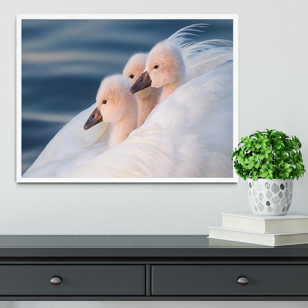 A beautifully framed print of three white swans, showcasing vibrant colors and elegant craftsmanship.