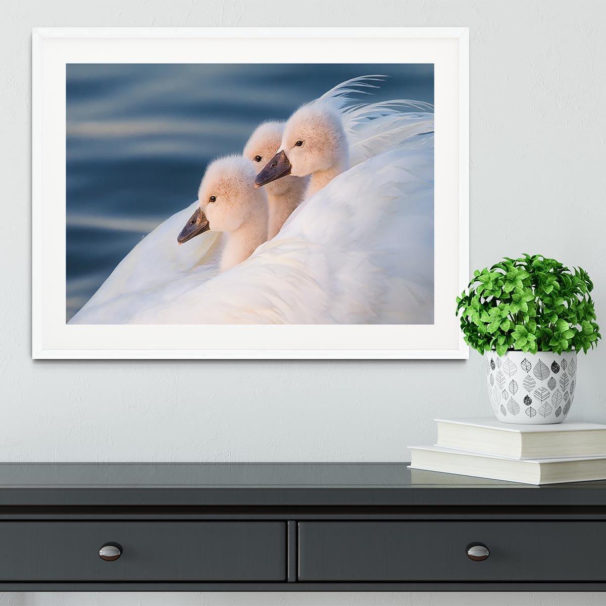 A beautifully framed print of three white swans, showcasing vibrant colors and elegant craftsmanship.