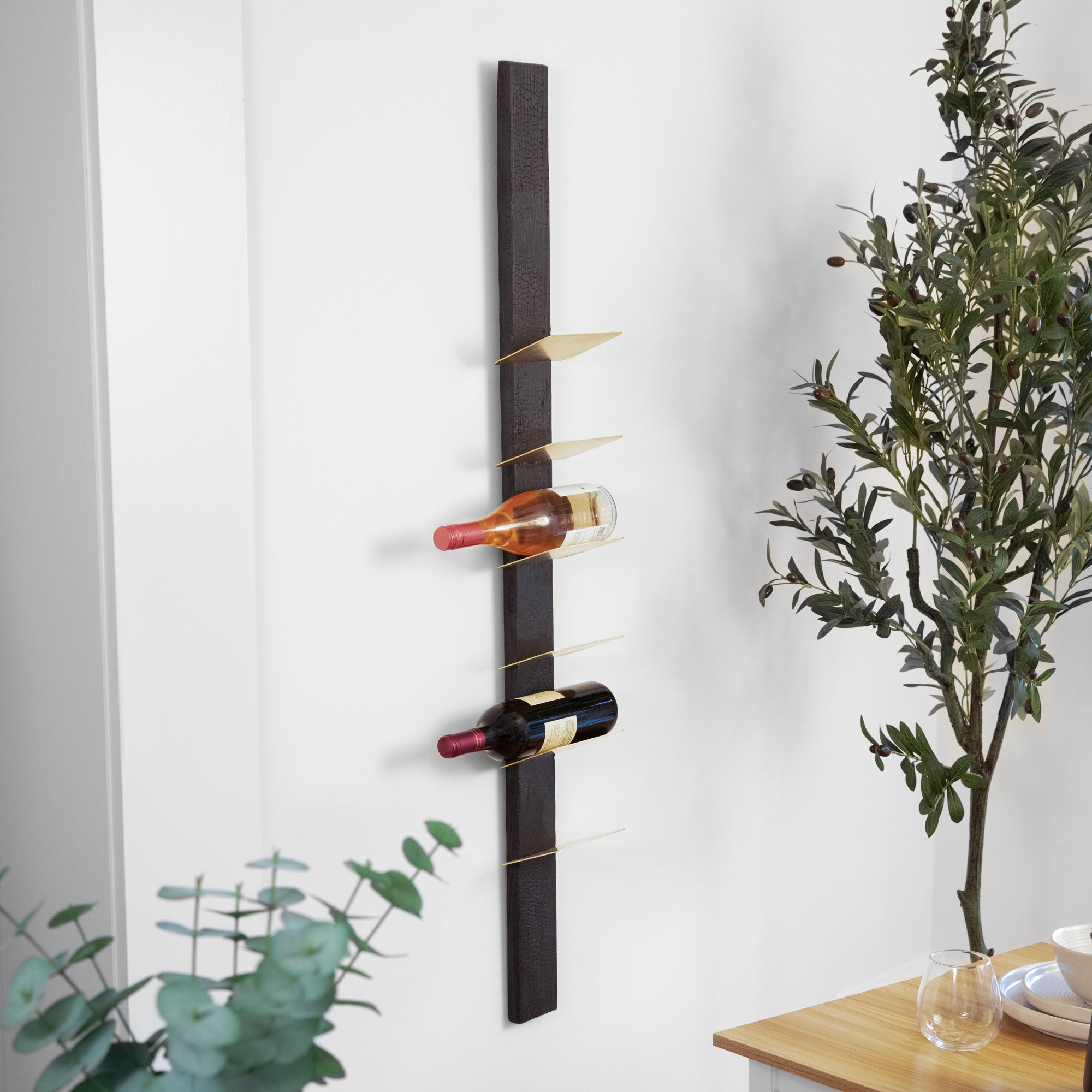 Stylish TIPsy wine rack displaying wine bottles, crafted from repurposed wood with brushed brass accents.