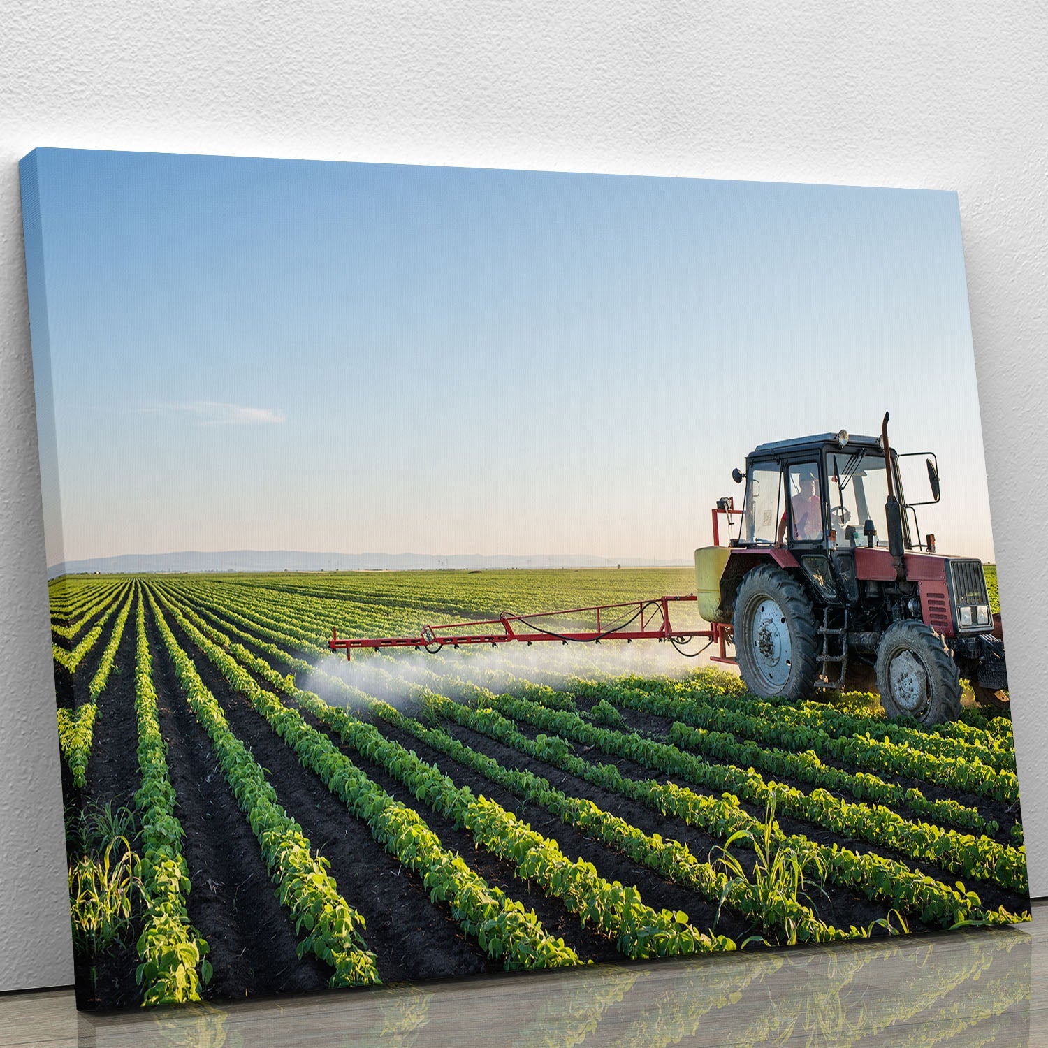 A vibrant canvas print of a tractor spraying in a lush green field, showcasing rural beauty and agricultural life.