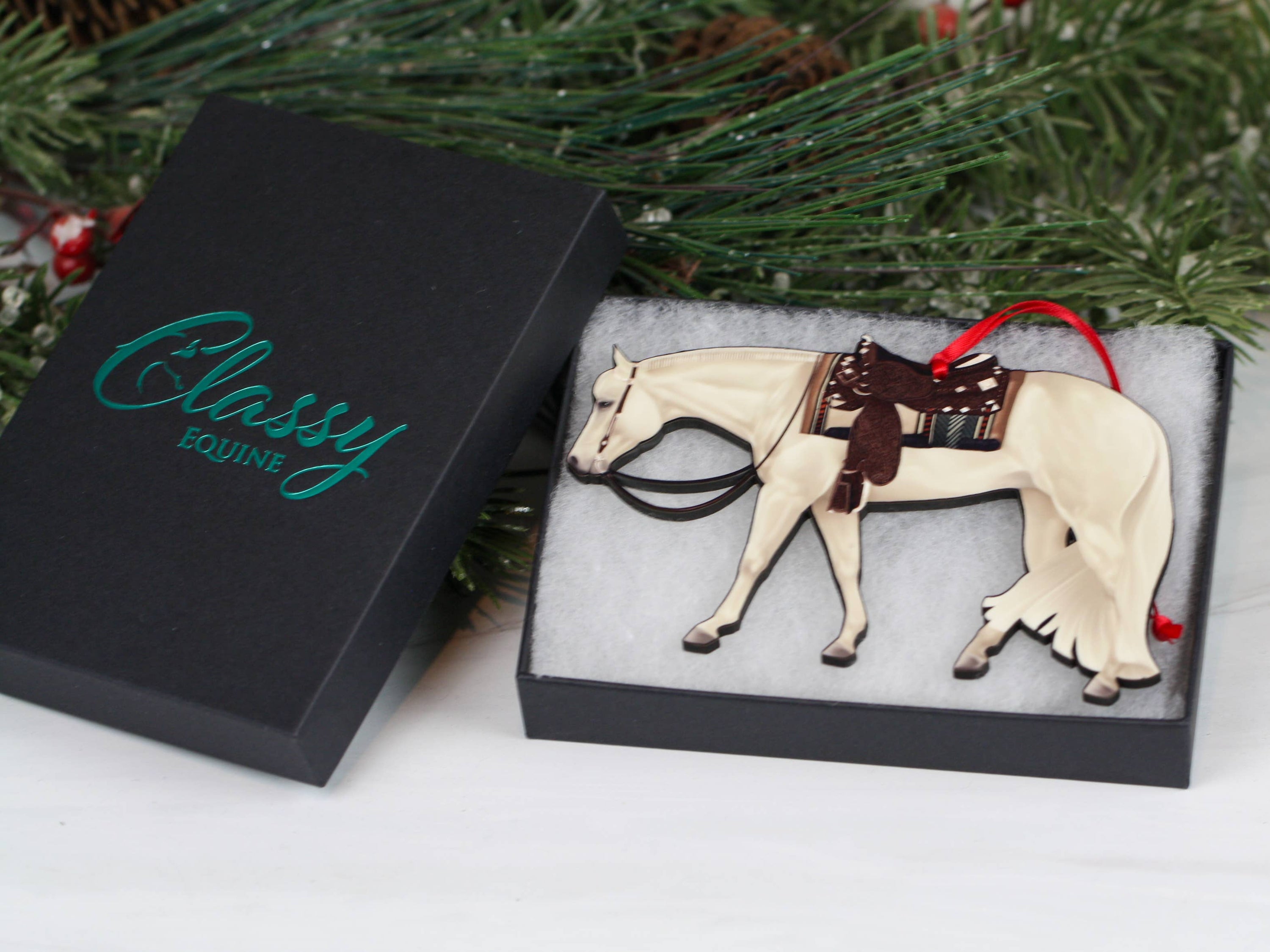 Gray and white Quarter Horse ornament made of composite wood, featuring red and black ribbons for hanging.