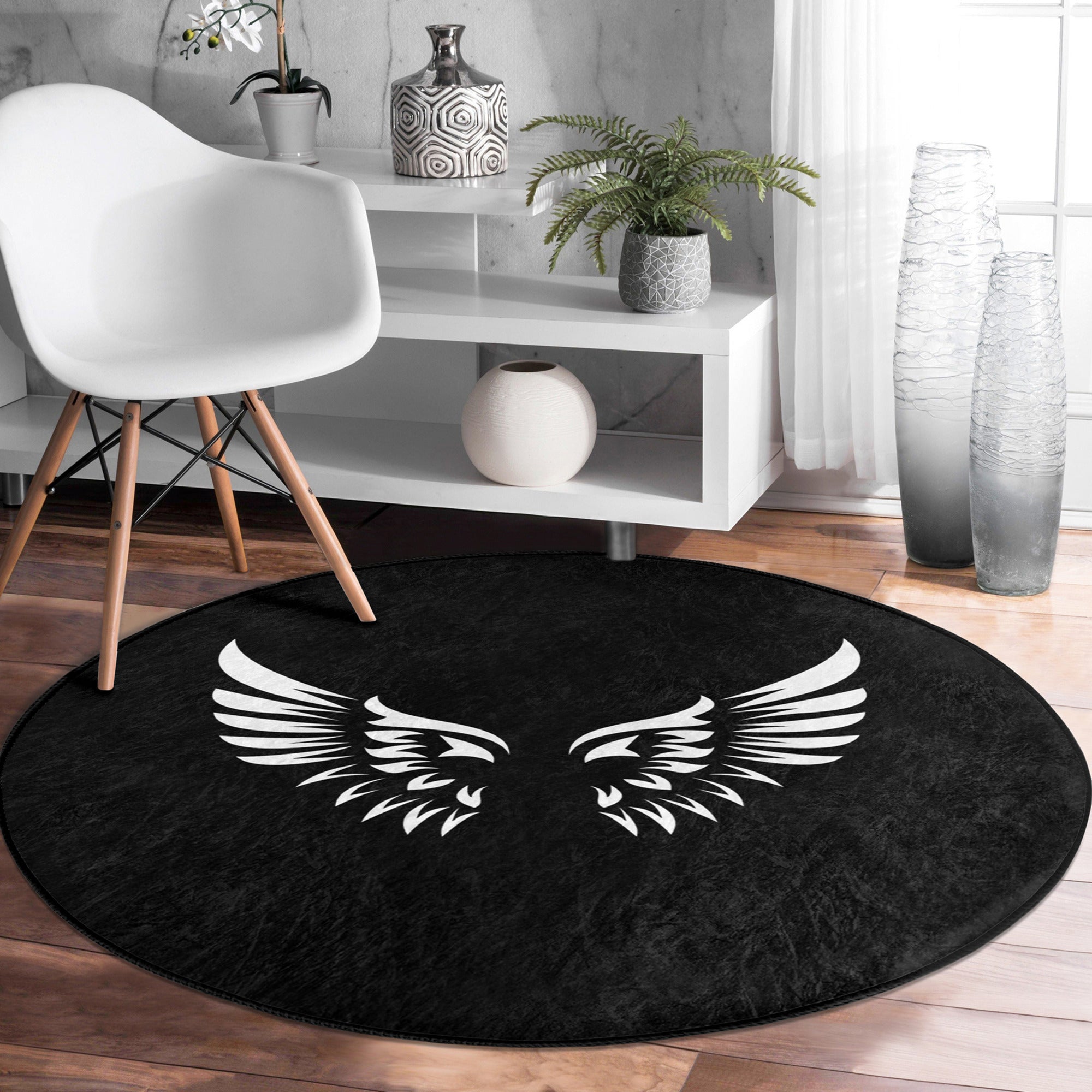 A round rug featuring white angel wings design on a black background, showcasing its soft velvet texture and elegant appearance.