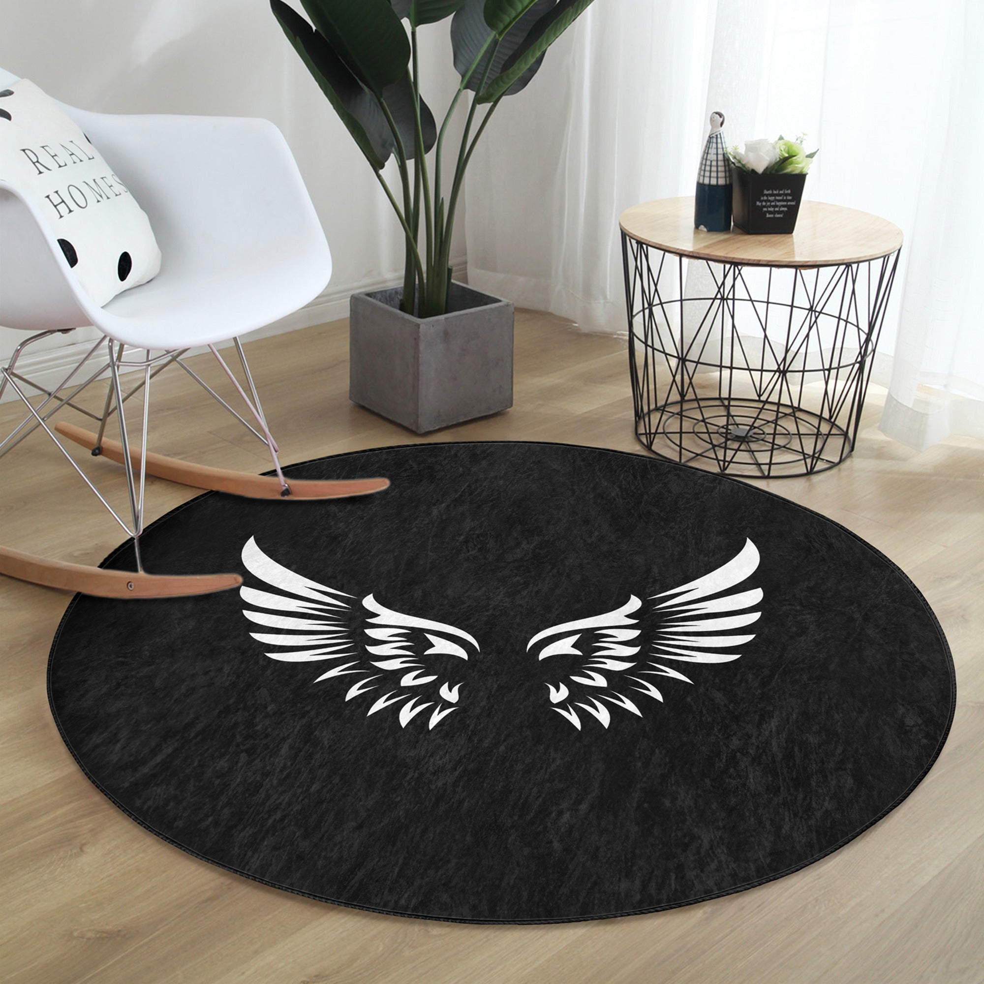A round rug featuring white angel wings design on a black background, showcasing its soft velvet texture and elegant appearance.
