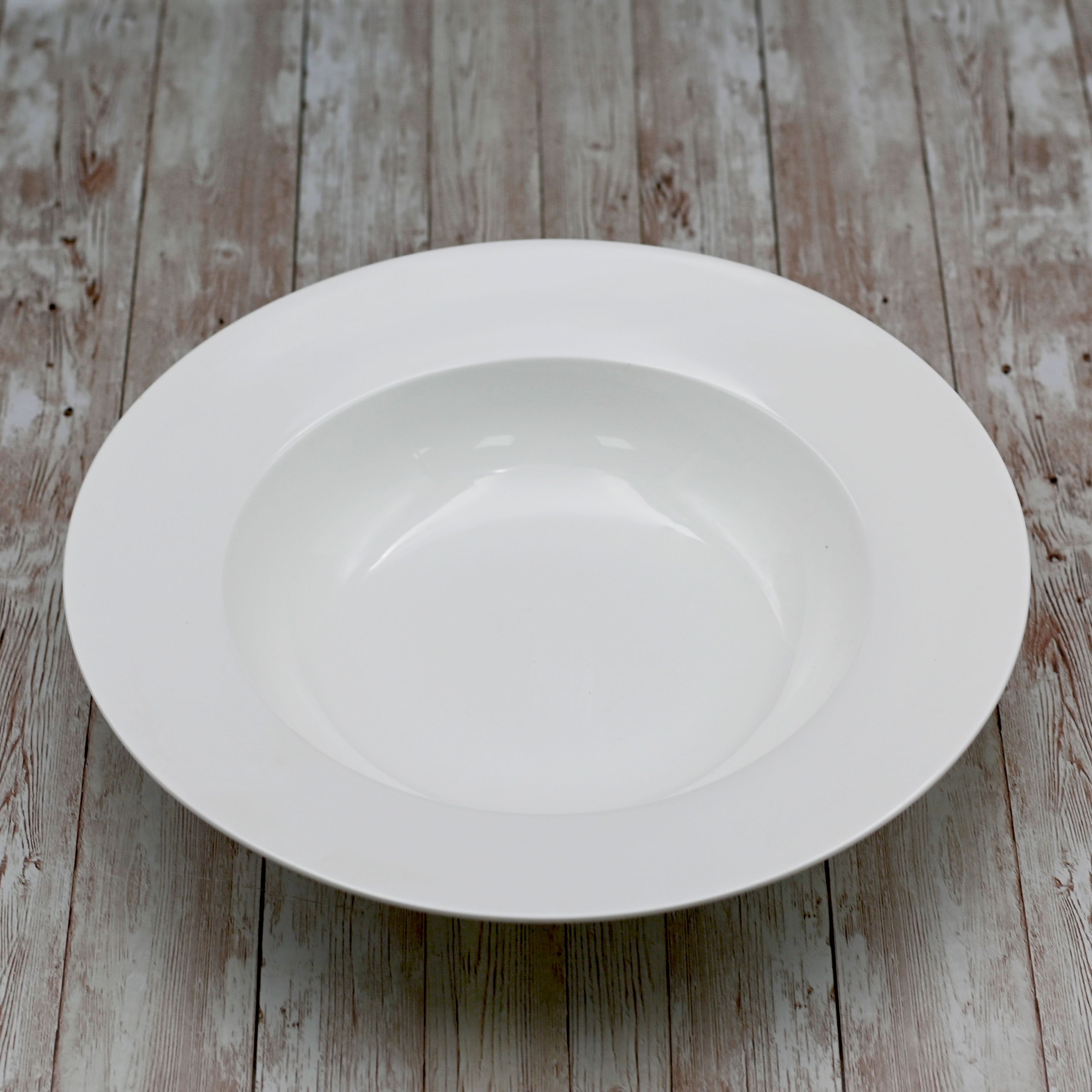 A 12-inch white deep plate made of fine porcelain, showcasing an elegant rolled rim design, perfect for serving soups and meals.