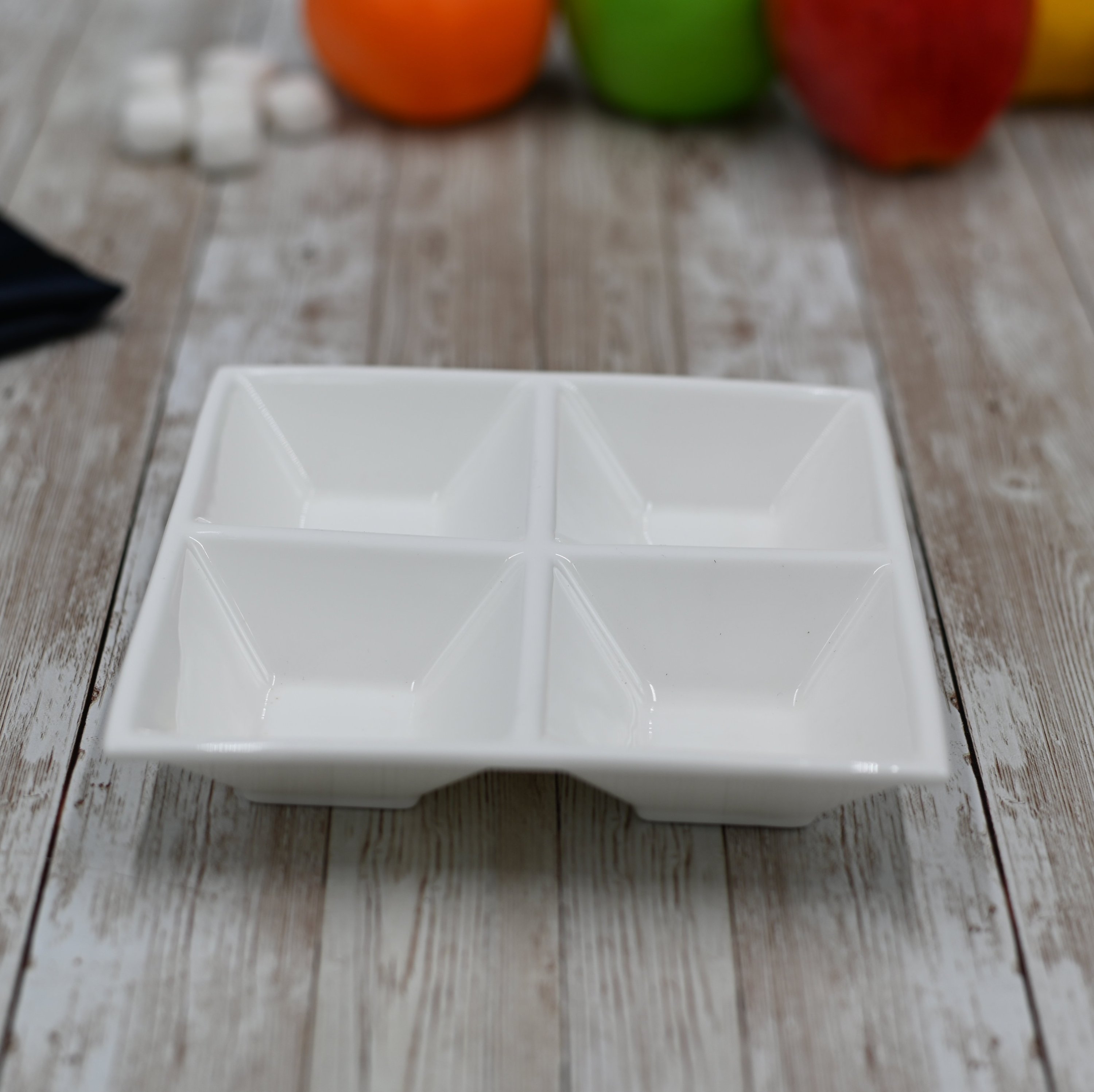 White divided square dish with four compartments, perfect for serving seafood and sushi elegantly.