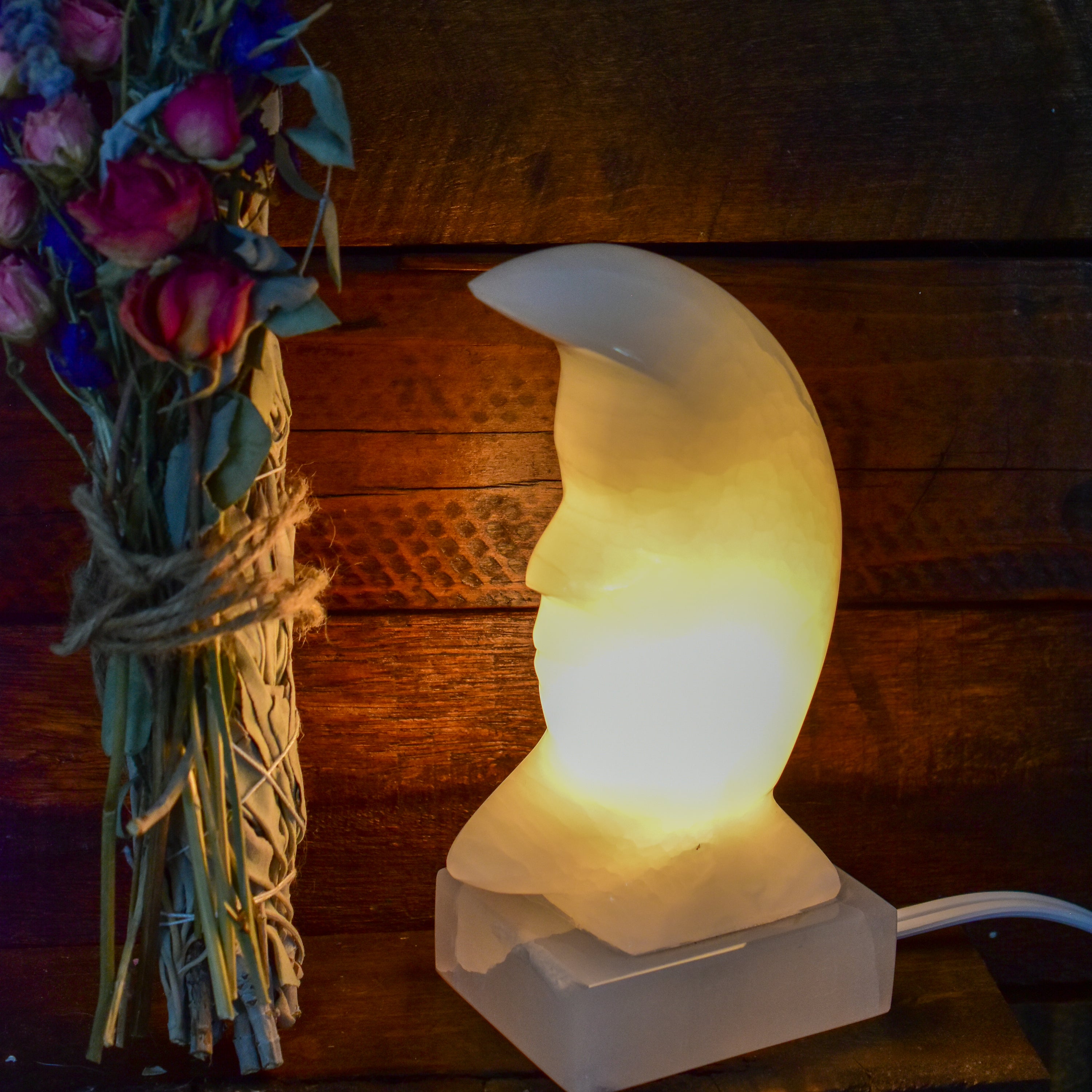 A beautifully crafted white onyx crescent moon lamp, hand carved and polished, showcasing intricate details and a warm glow.