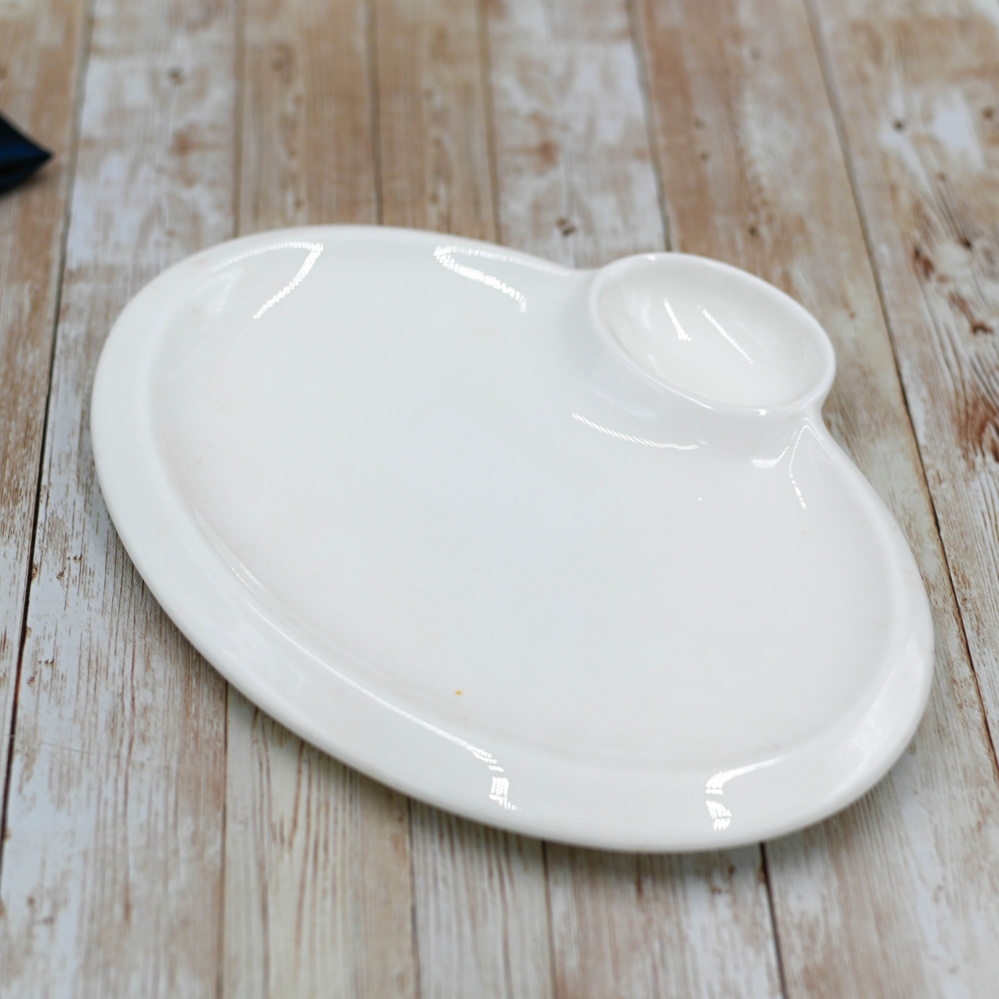 Elegant white oval platter with sauce compartment, perfect for serving various dishes.