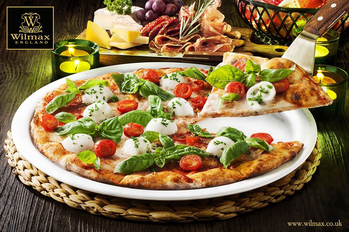 A stylish 14-inch white porcelain pizza plate with a rolled chip-resistant rim, perfect for serving pizzas elegantly.