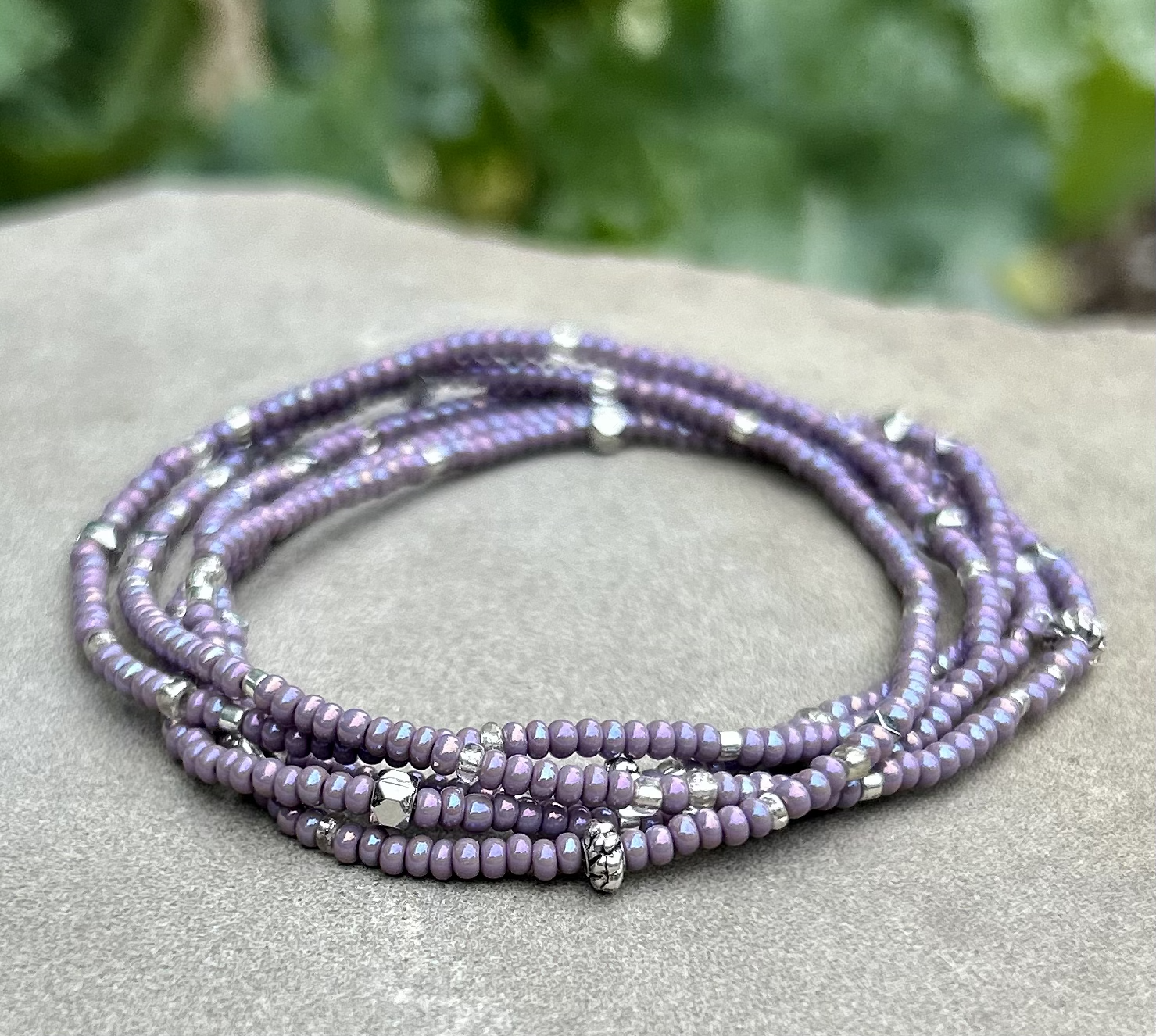 A stylish lilac and silver-sprinkled beaded wrap bracelet, showcasing Czech glass seed beads and metallic accents, elegantly wrapped around a wrist.