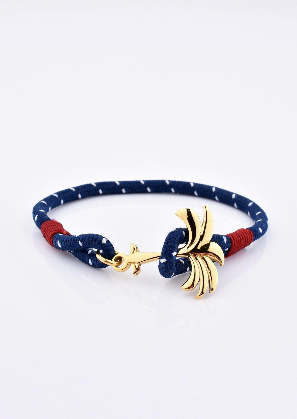 A stylish Palmband - Seven Seas bracelet featuring a blue and white nylon band with a unique gold palm tree anchor.