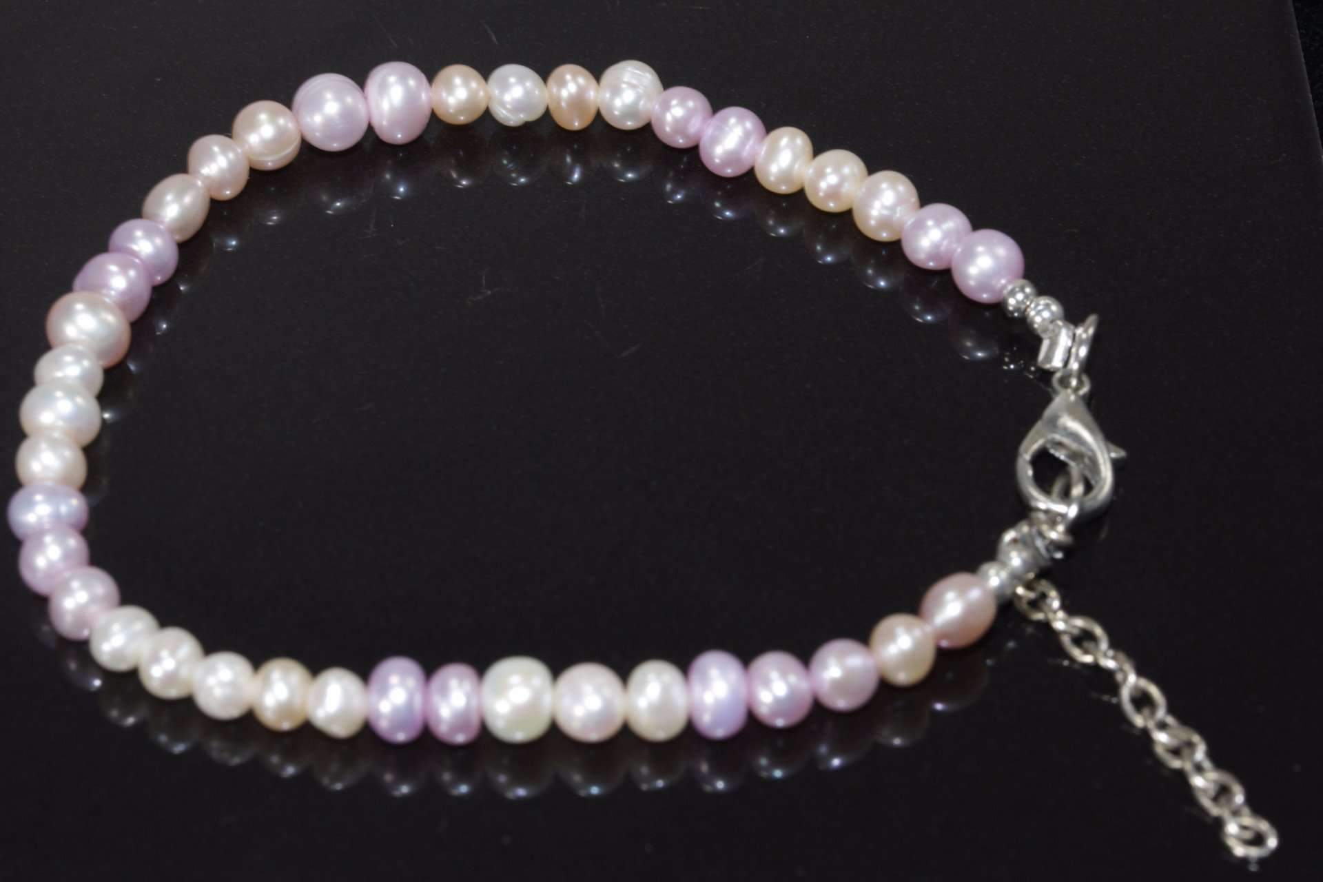 A delicate Pearly Pink Sands Bracelet featuring cultured pearls in soft pink and creamy nude shades, elegantly displayed on a white background.