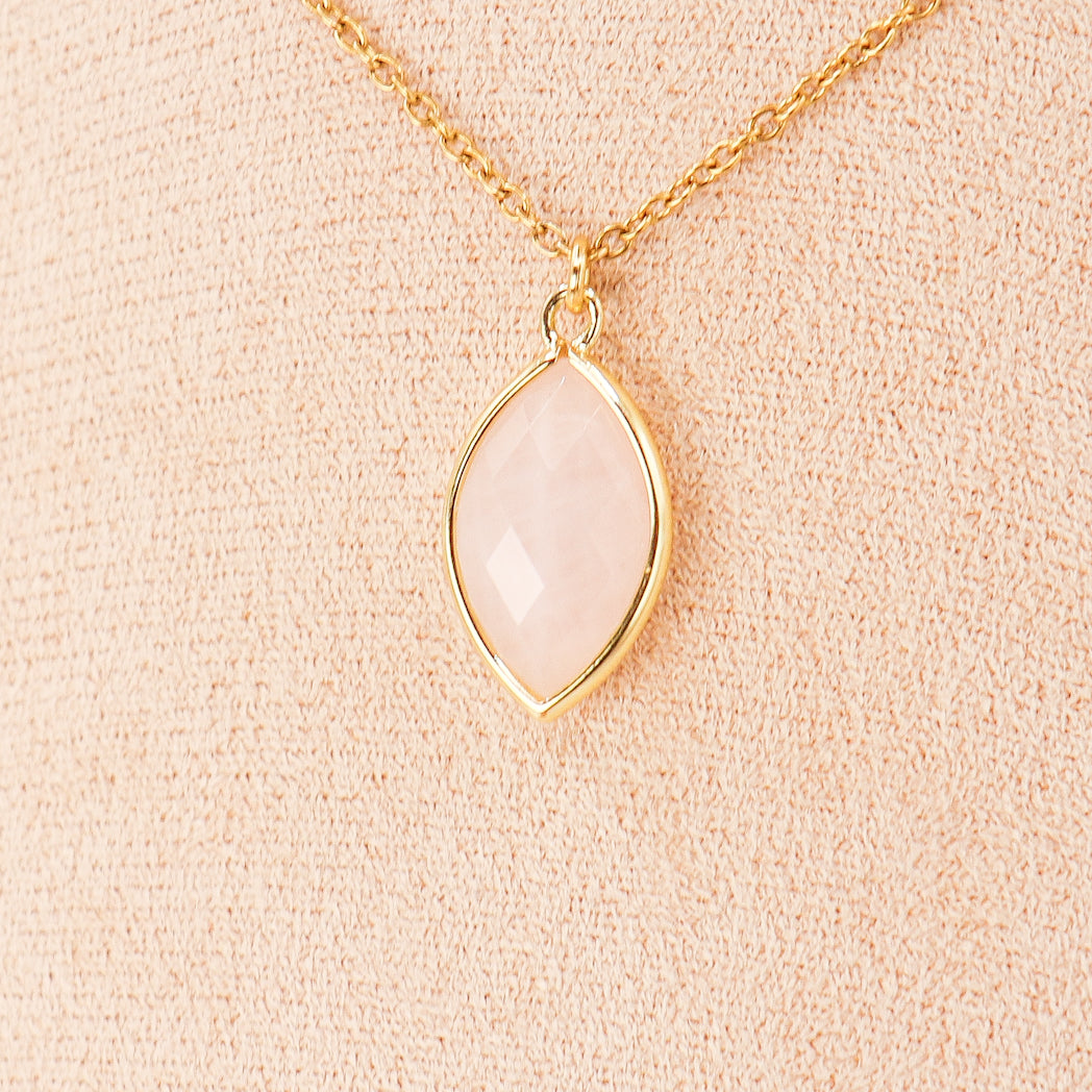 Pendentif amande en quartz rose avec sertissage en laiton doré, élégant et unique, suspendu à un cordon en cuir.