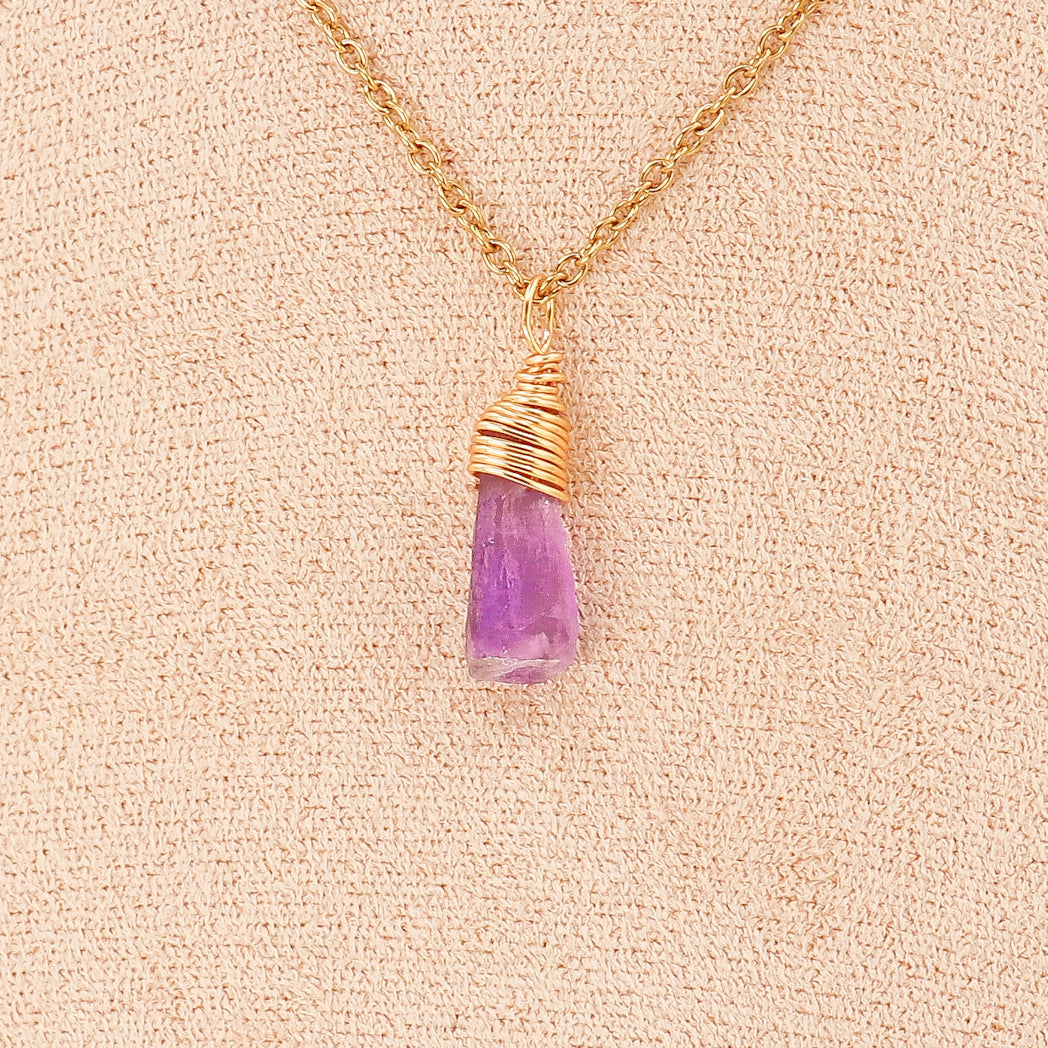 Pendentif en améthyste brute avec cuivre plaqué or, unique et élégant, suspendu à un cordon en cuir.