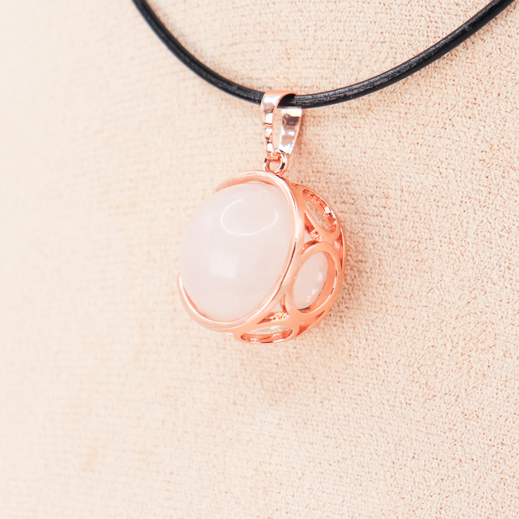 Pendentif en Quartz rose naturel en forme de sphère, serti en laiton doré rose, suspendu à un cordon en cuir.
