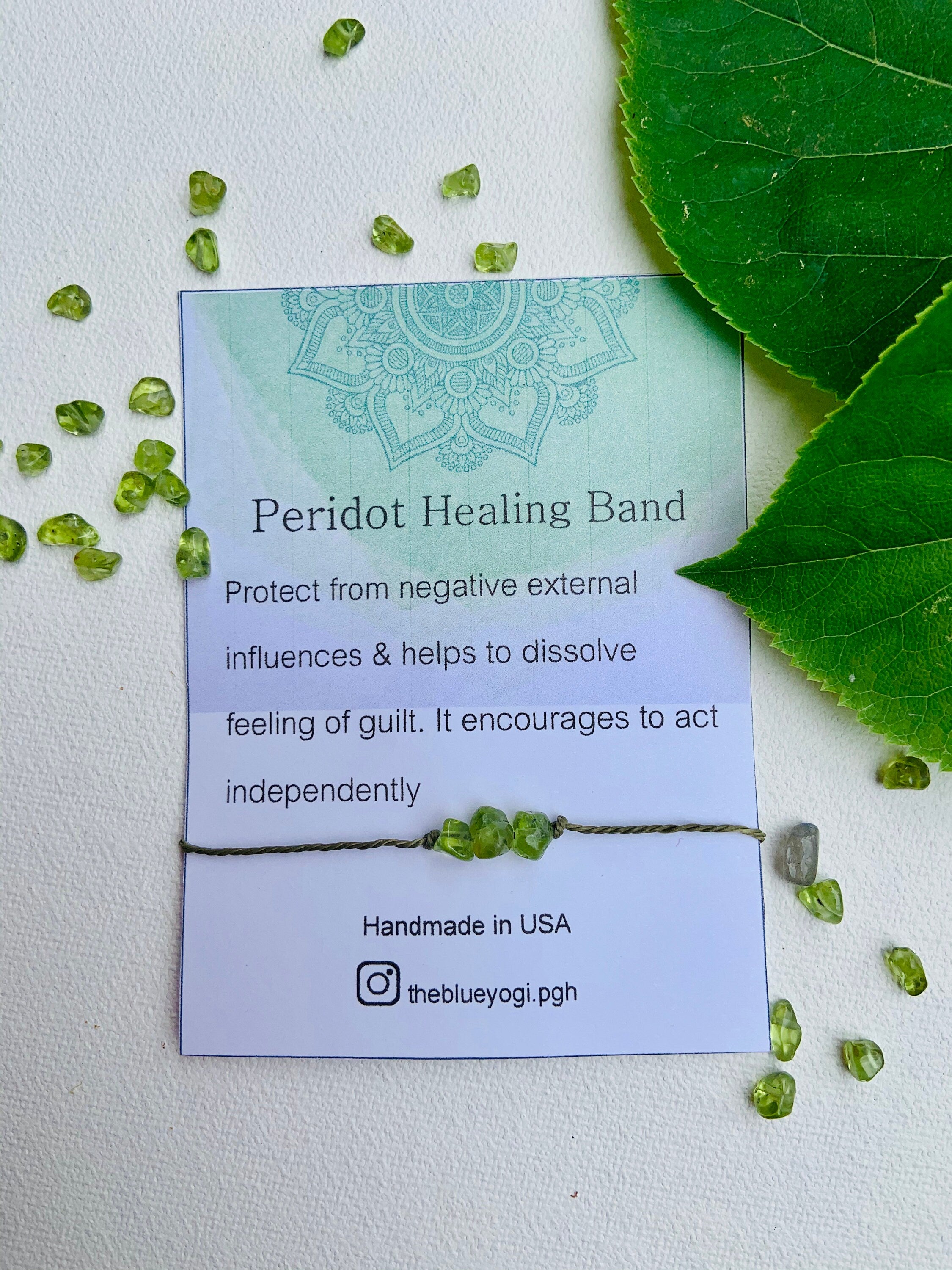 A handcrafted Peridot Gemstone Power Band featuring natural gemstones with a tie closure, displayed with a watercolor Mandala art card.