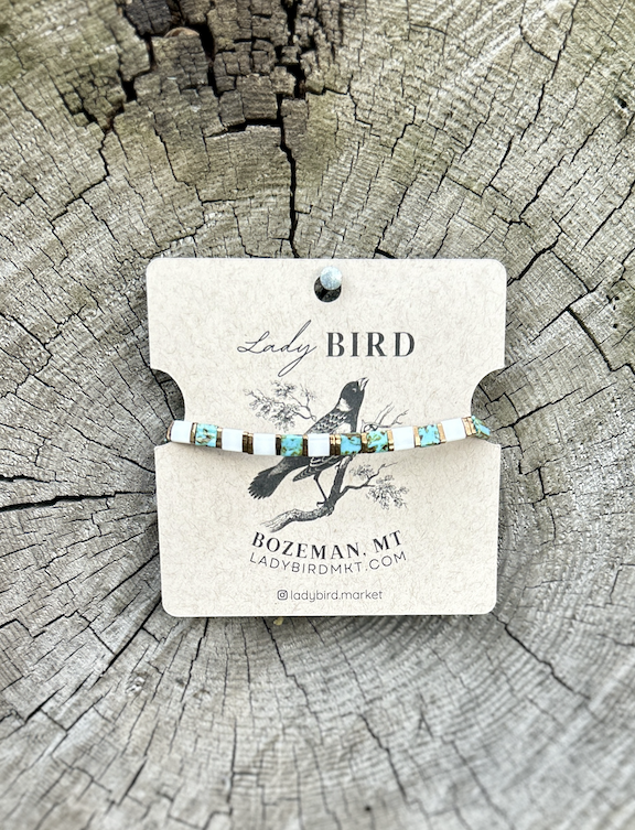 A pair of elegant speckled turquoise earrings featuring gold and silver Tila beads, showcasing a bohemian style.