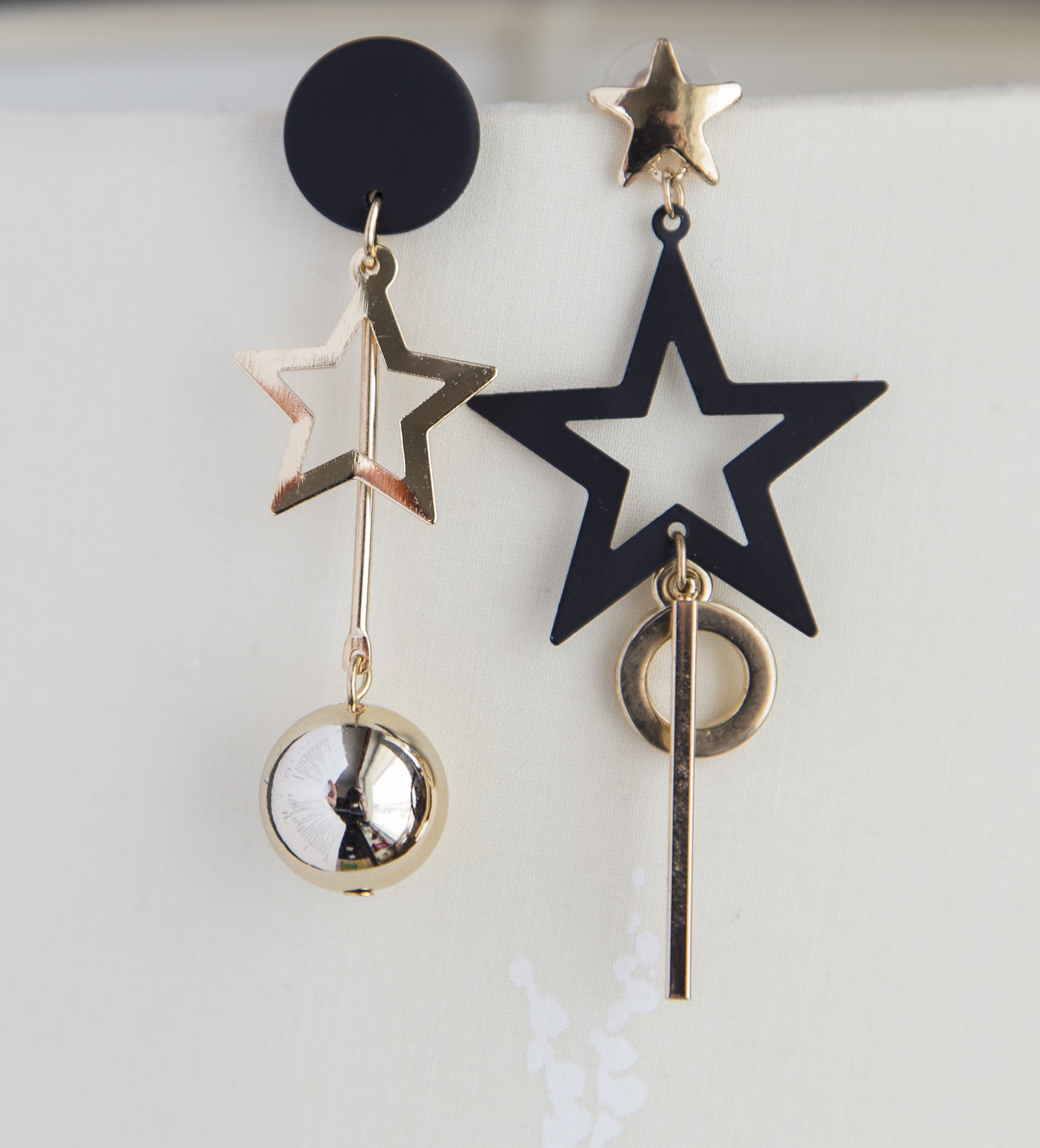 Asymmetrical star boho earrings featuring gold and black metal, showcasing a unique design with stars and a hanging ball.