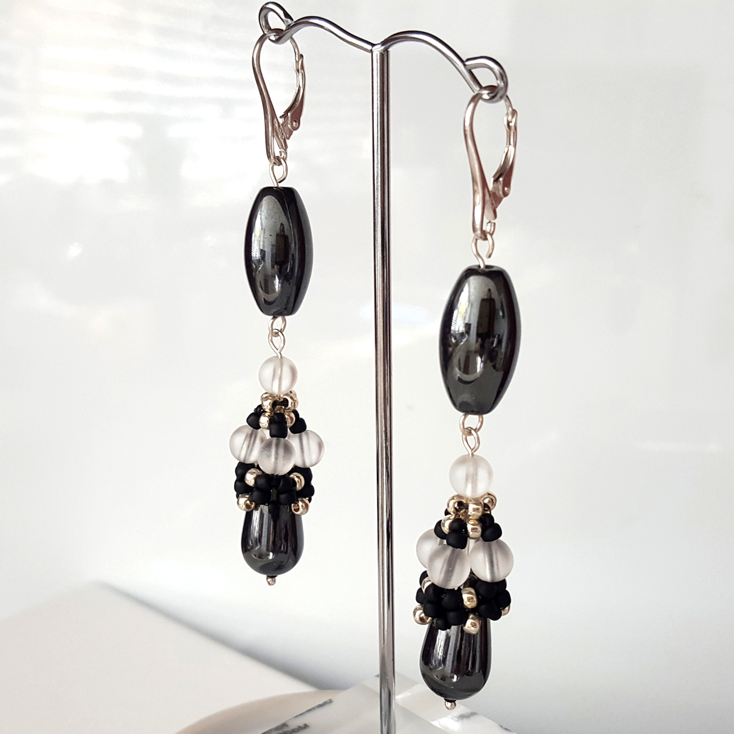Haematite Long Dangle Earrings featuring teardrop beads and frosted clear crystals, hanging from Sterling Silver Lever Back hooks.