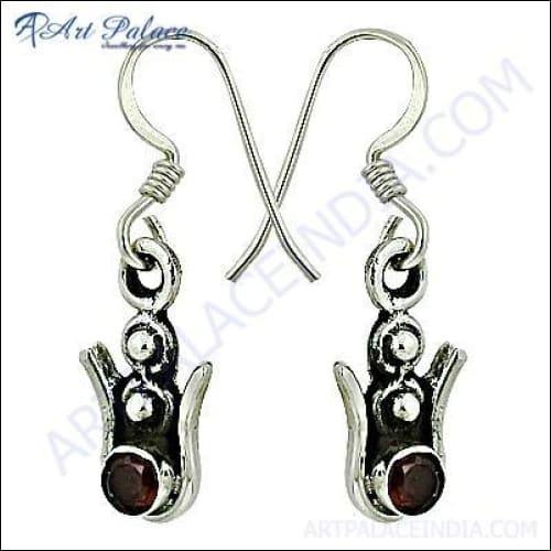 A pair of handcrafted silver earrings featuring vibrant garnet gemstones, showcasing intricate design and craftsmanship.