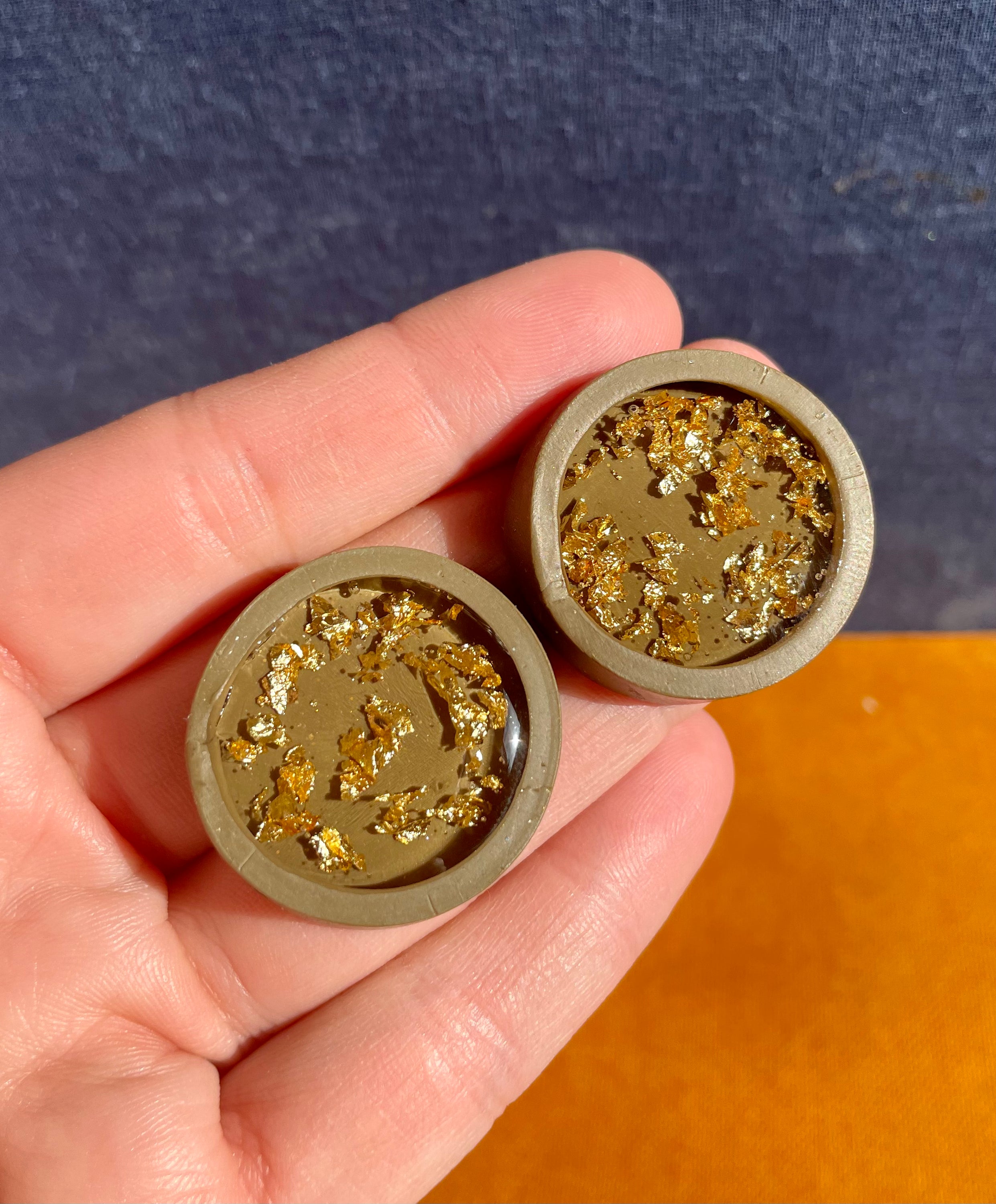 A pair of large gold flecked stud earrings, handmade with unique patterns and lightweight design, featuring stainless steel hooks.