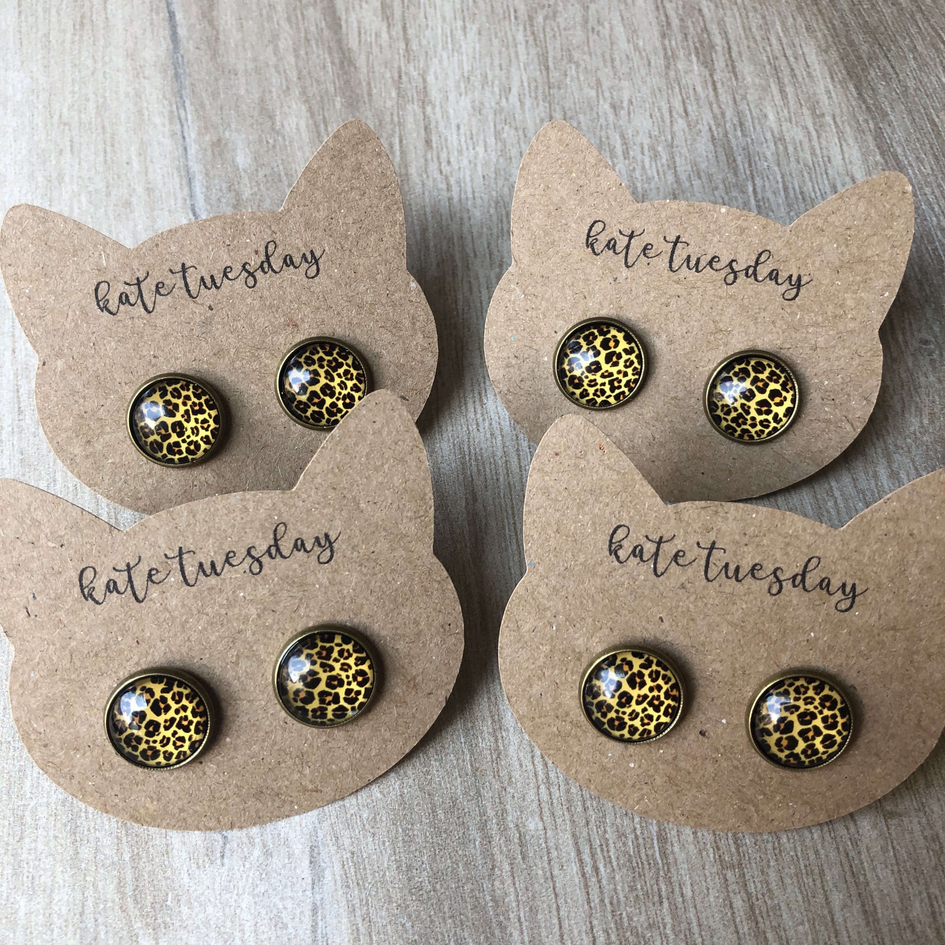 Meow Cheetah Earrings featuring a 12mm cheetah design on bronze settings, displayed on a brown cat card.