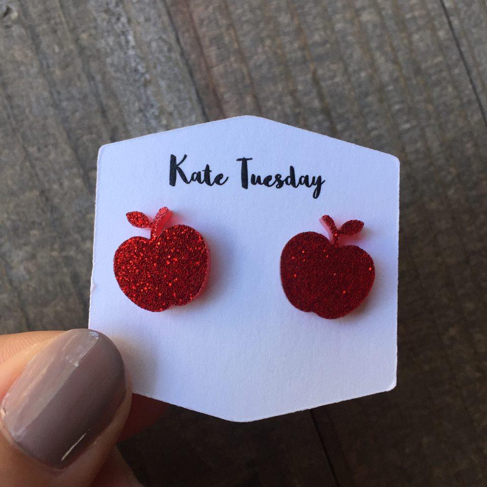 A pair of vibrant red sparkly apple stud earrings made from acrylic, showcasing a playful design with a shiny finish.