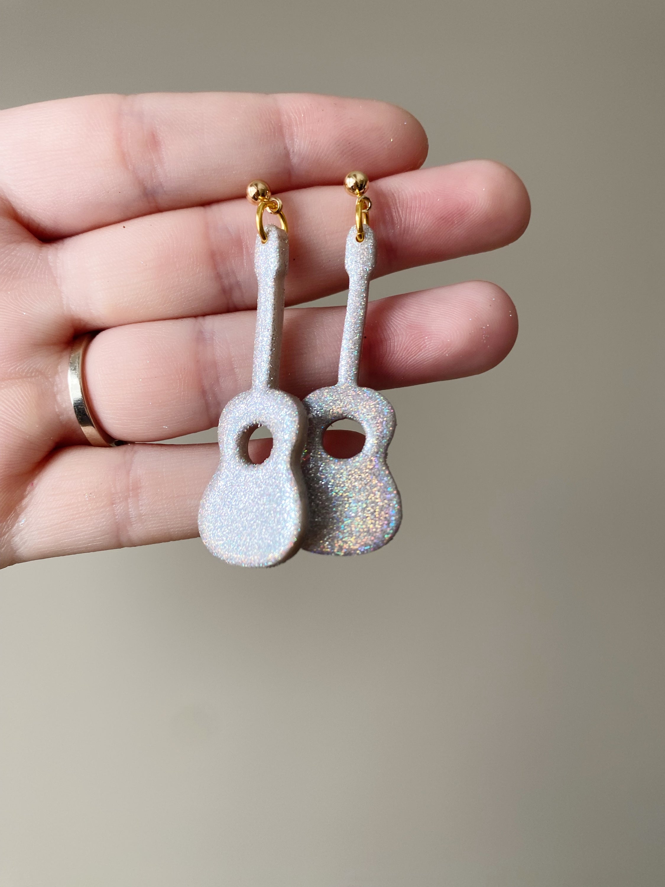 Handmade polymer clay earrings in the shape of a sparkly guitar, showcasing vibrant colors and unique design, perfect for music lovers.