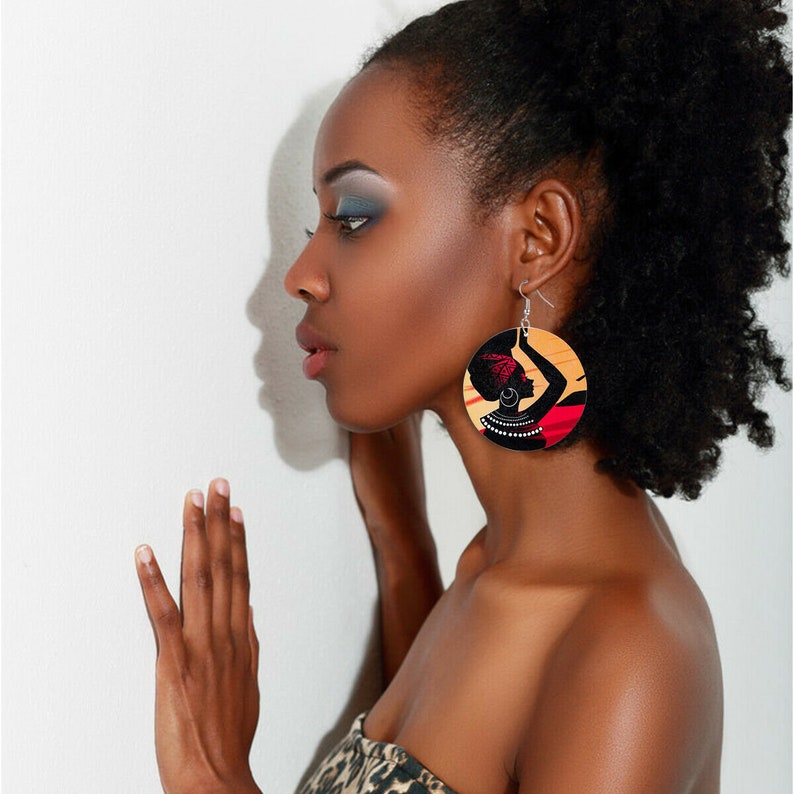 A pair of handcrafted wooden earrings featuring a painted African woman design, showcasing vibrant colors and ethnic artistry.