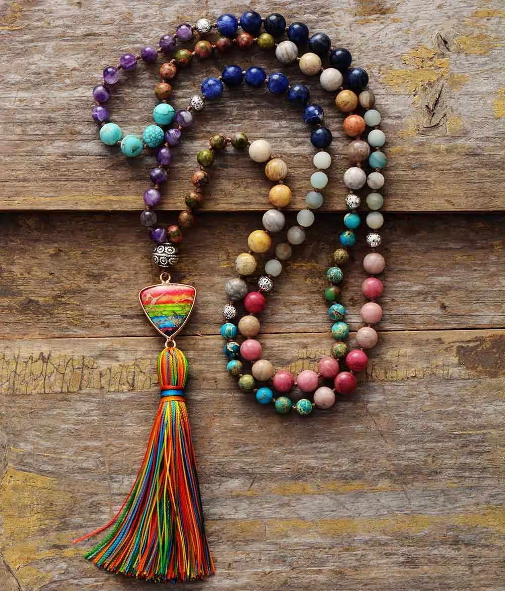 A handmade 7 Chakra Triangle Charm Tassel Necklace featuring colorful natural healing stones and a triangle charm.