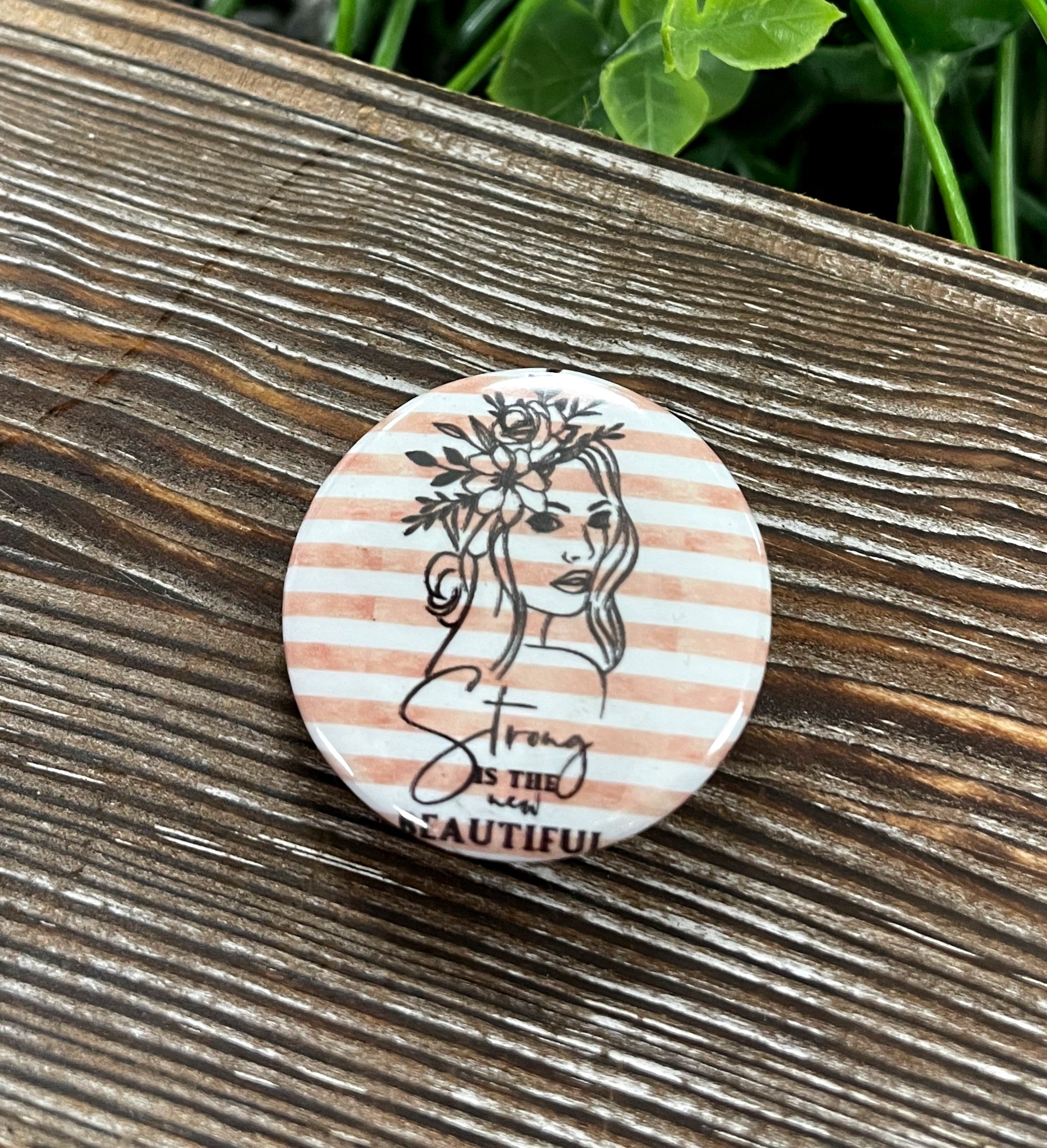 A vibrant 1.25-inch striped graphic art button with a plastic back, showcasing a colorful design.