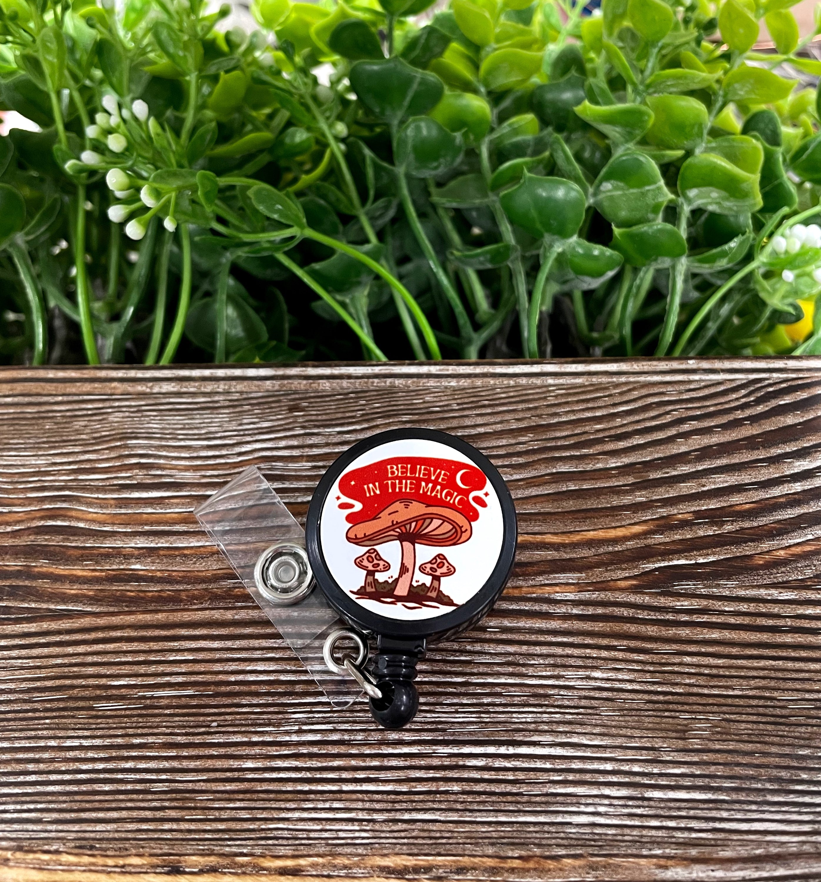 Retractable black badge reel featuring a colorful magic mushroom design on a metal blank.