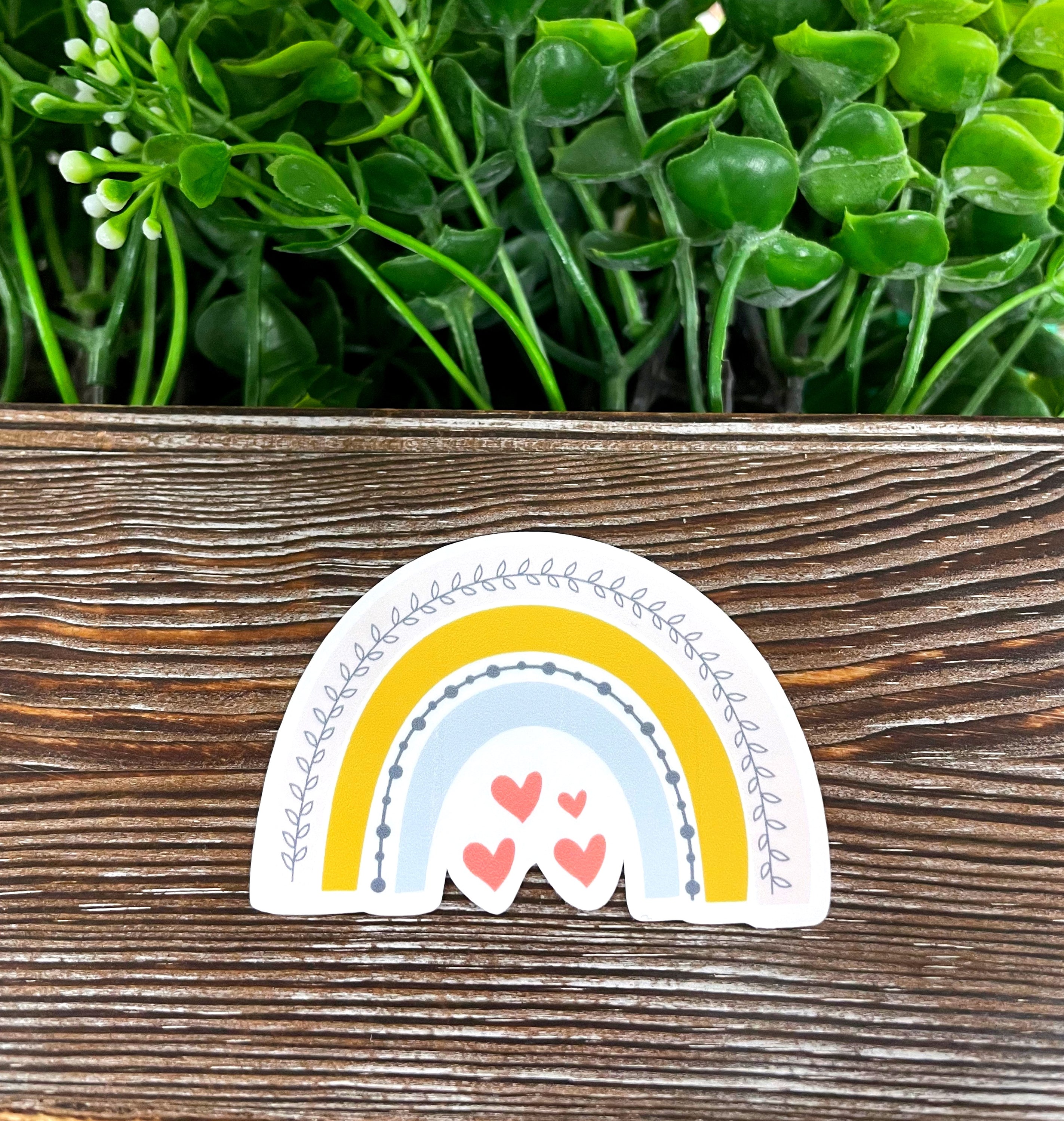 Black Rainbow Sticker with Hearts on a smooth surface, showcasing vibrant colors and intricate design.