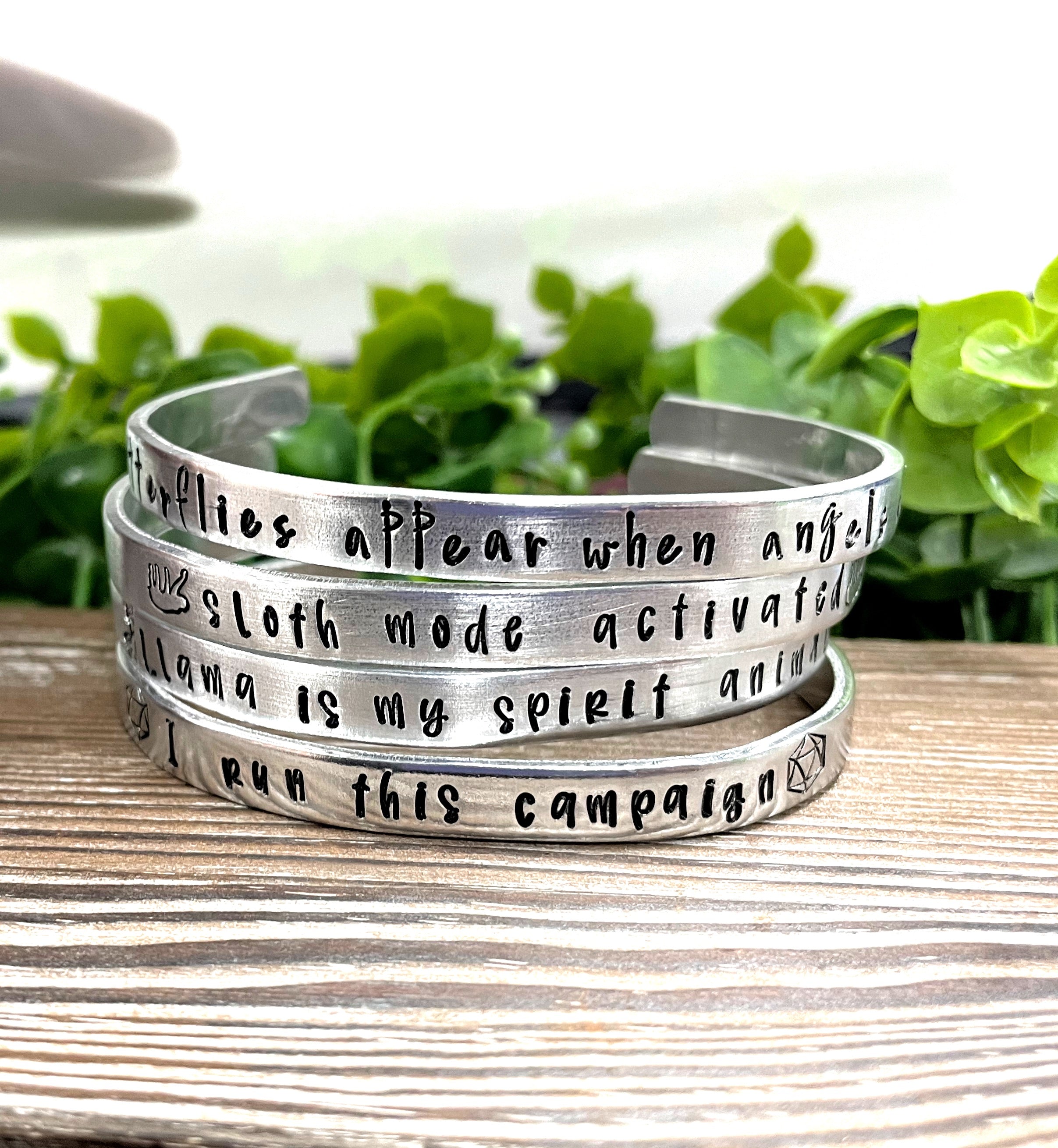 Hand-stamped aluminum cuff bracelet with the phrase 'Butterflies Appear when Angels are Near', showcasing unique letter variations.