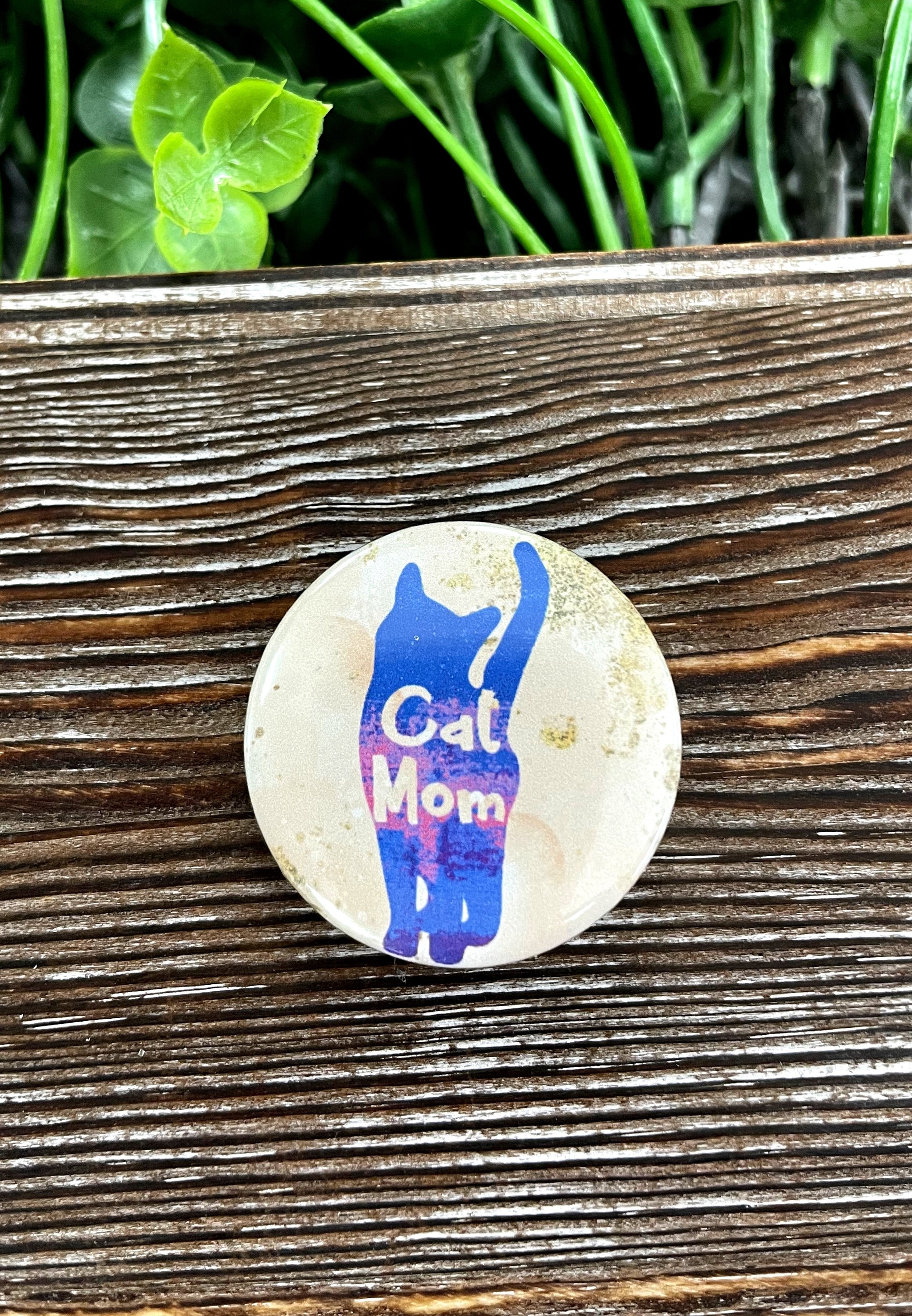 A colorful 1.25-inch Cat Mom graphic art button with a playful design, perfect for accessories.